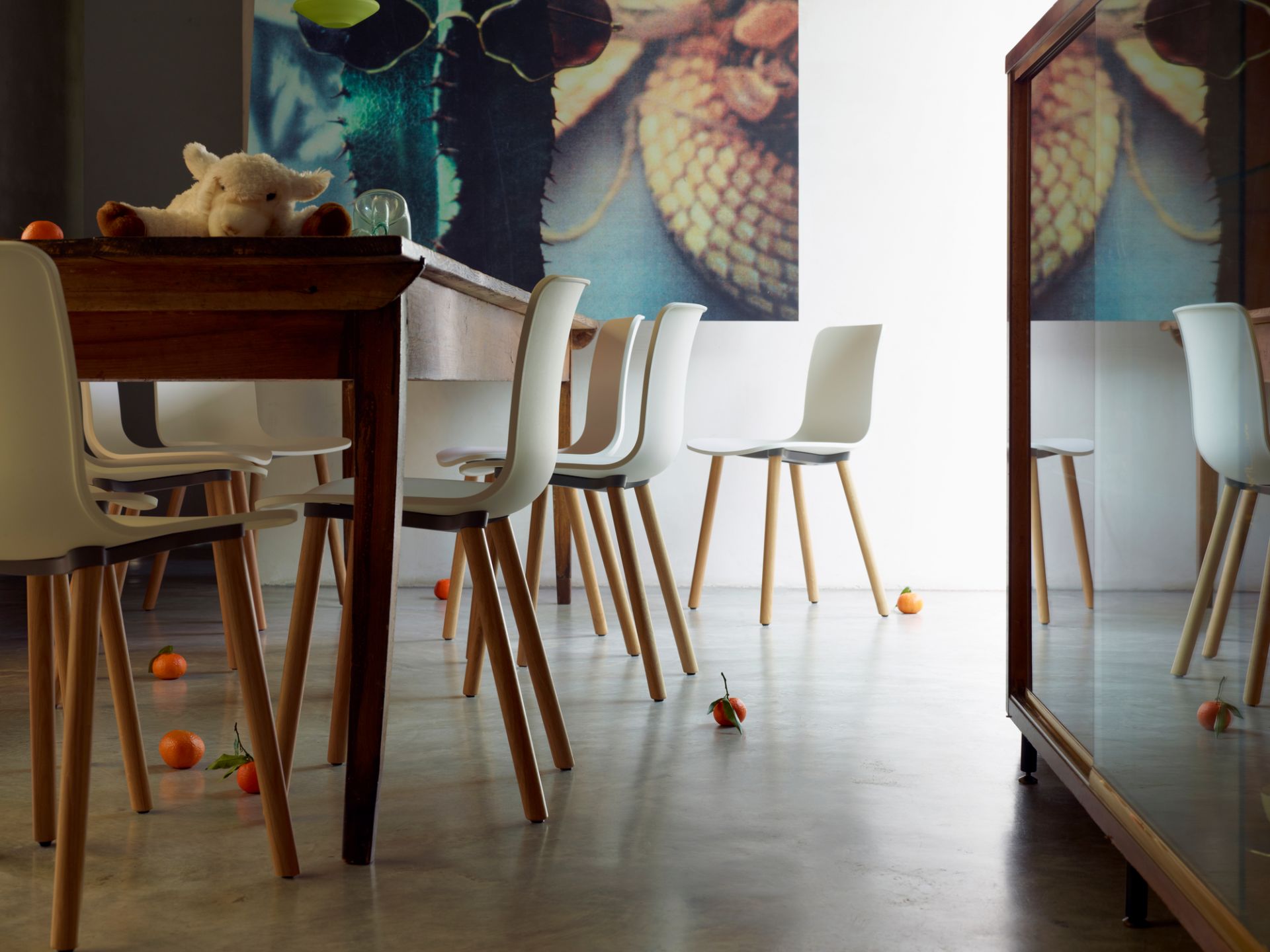 Innenaufnahme von weißen Hal Ply Wood Stühlen von Vitra mit Holzbeinen an einem Esstisch.