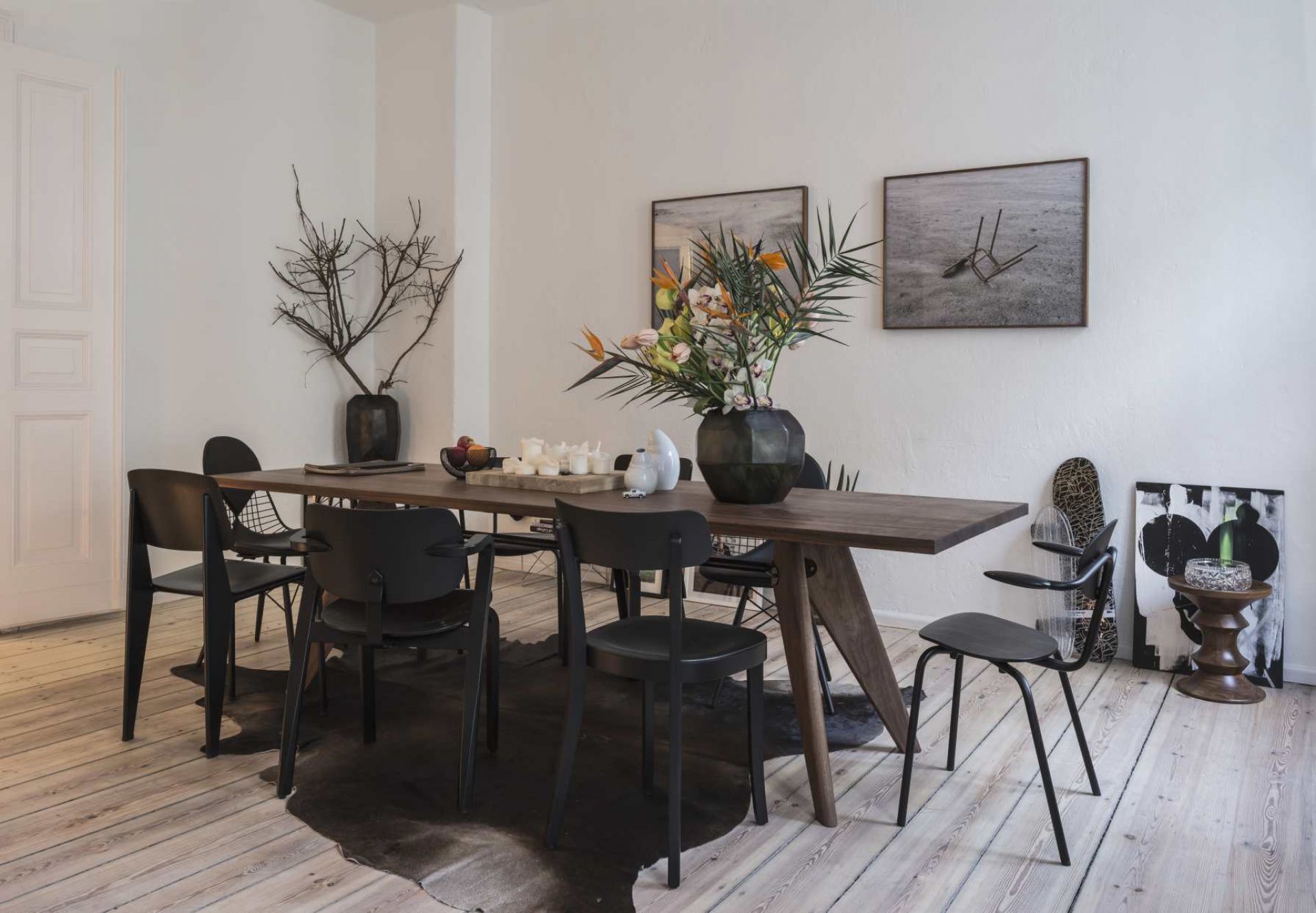 Esszimmer mit Vitra Table S.A.M Bois Tisch, Holzoberfläche, schwarzen Stühlen und moderner Dekoration.