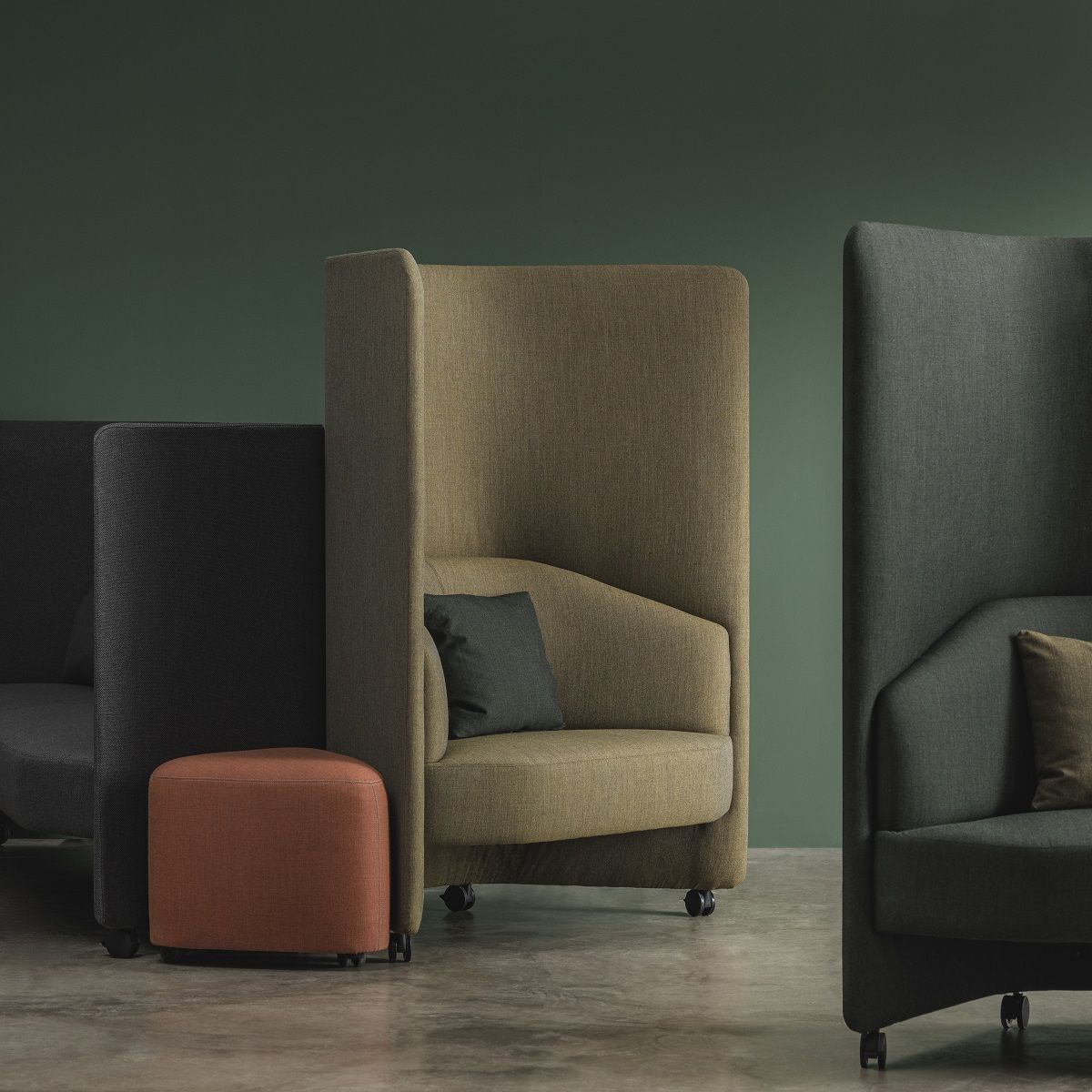 In Out Office Loungesessel mit hohem Panel in Beige, Grau und Schwarz, ergänzt durch einen orangefarbenen Hocker.