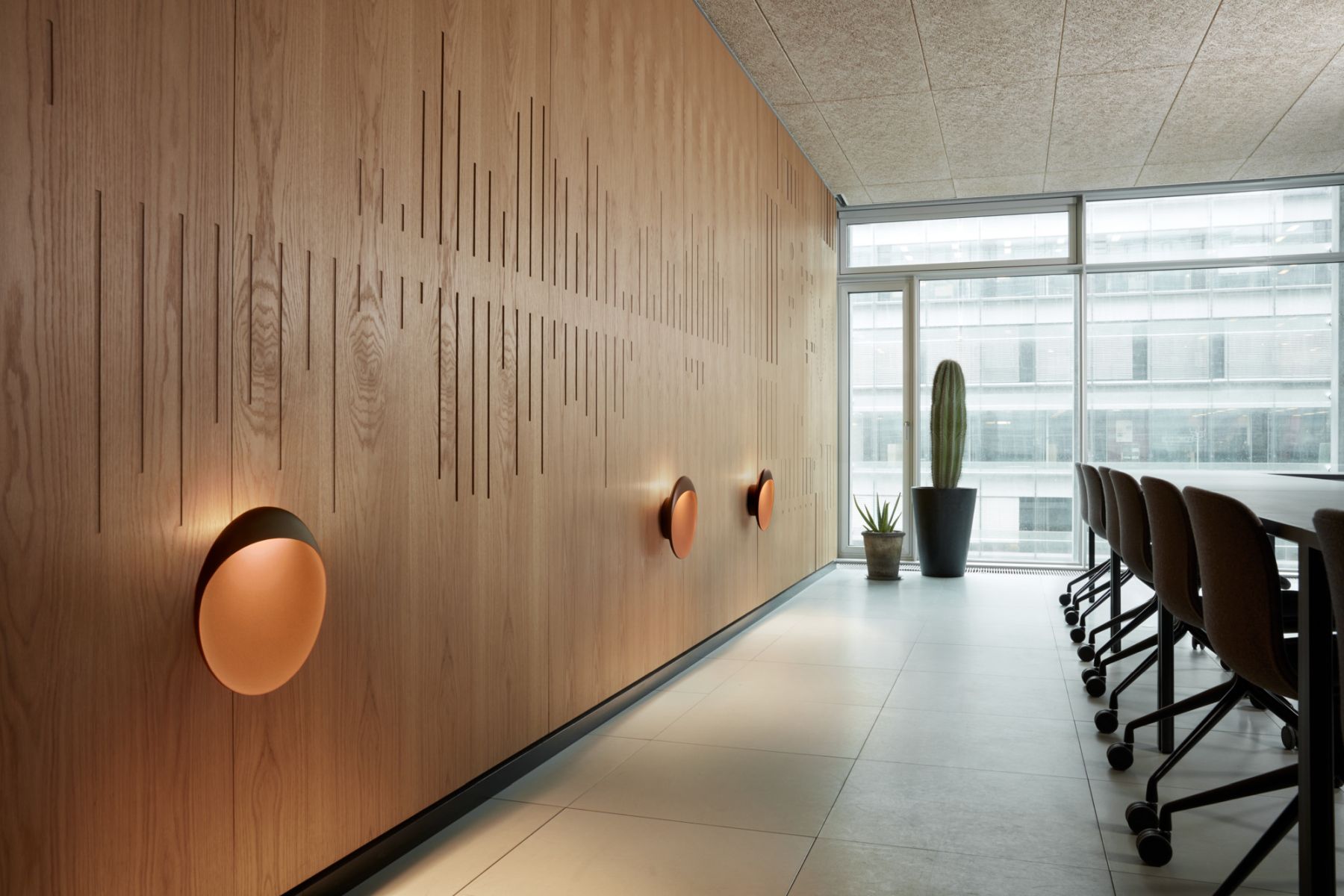 Flindt Wandleuchte von Louis Poulsen in einem modernen Büro mit Holzvertäfelung und Konferenzraum.