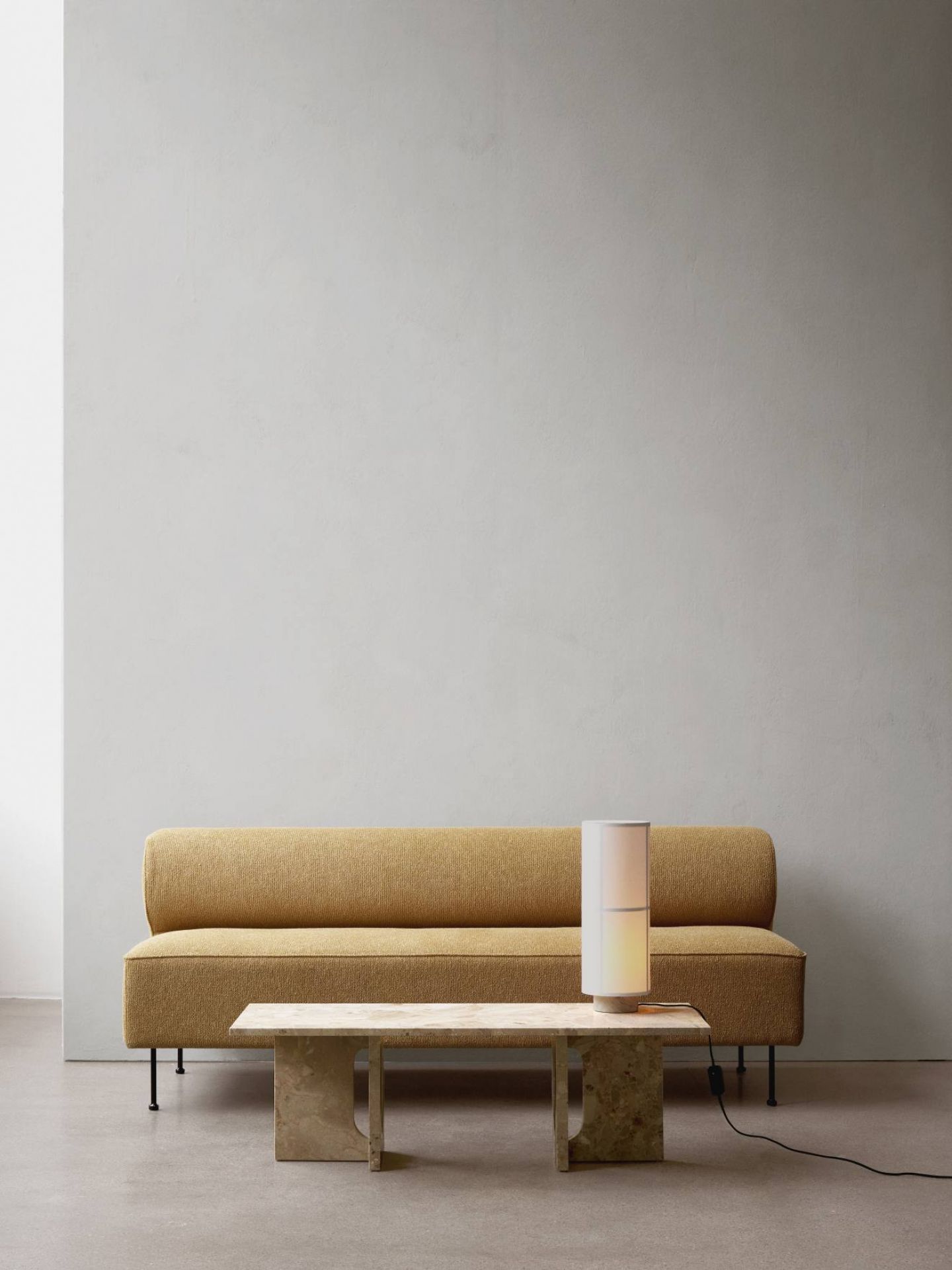 Audo Hashira Tischleuchte auf Marmortisch neben gelbem Sofa, moderne Innenraumbeleuchtung.