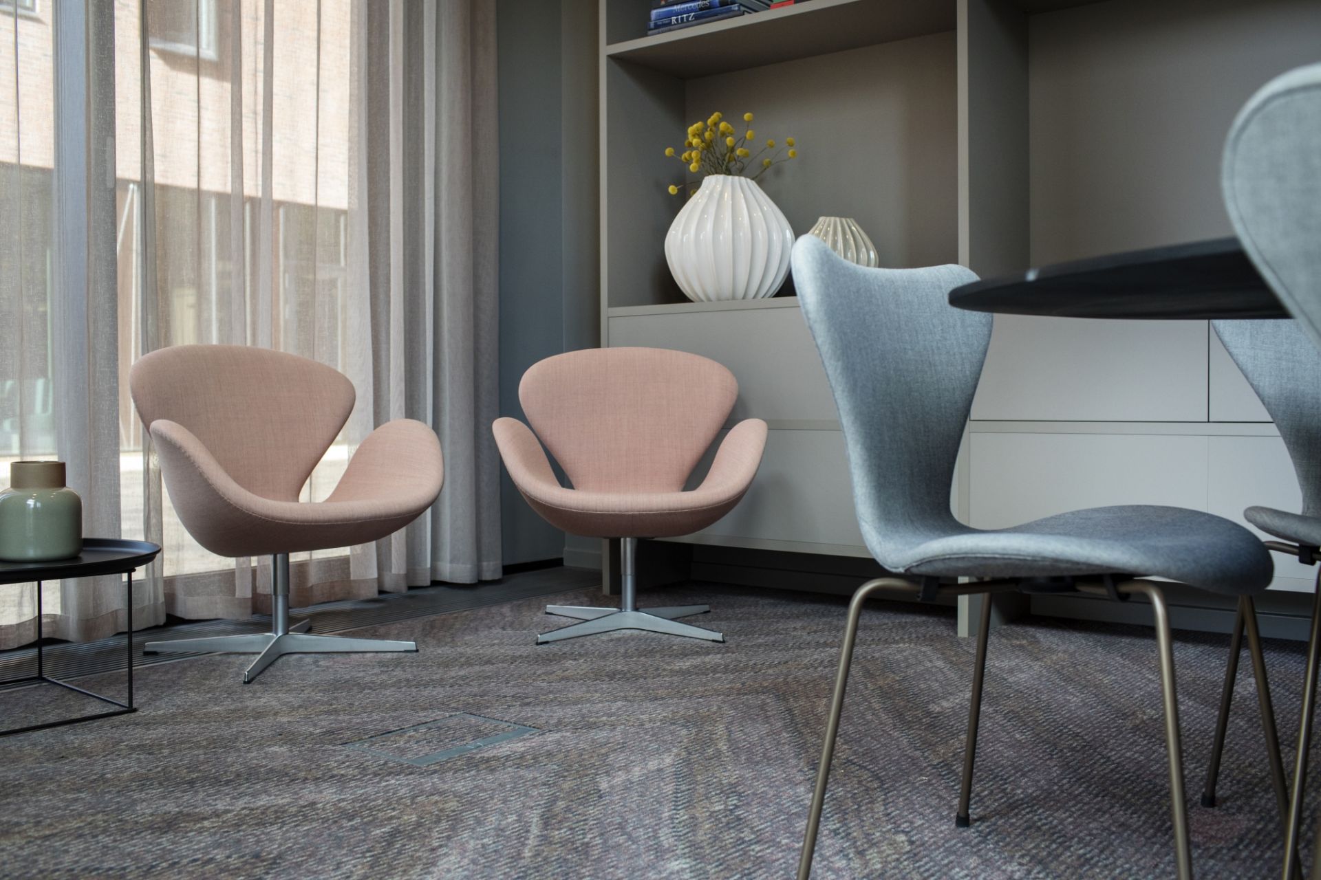 Zwei rosa Swan Chairs von Fritz Hansen und graue Stühle an einem Esstisch.