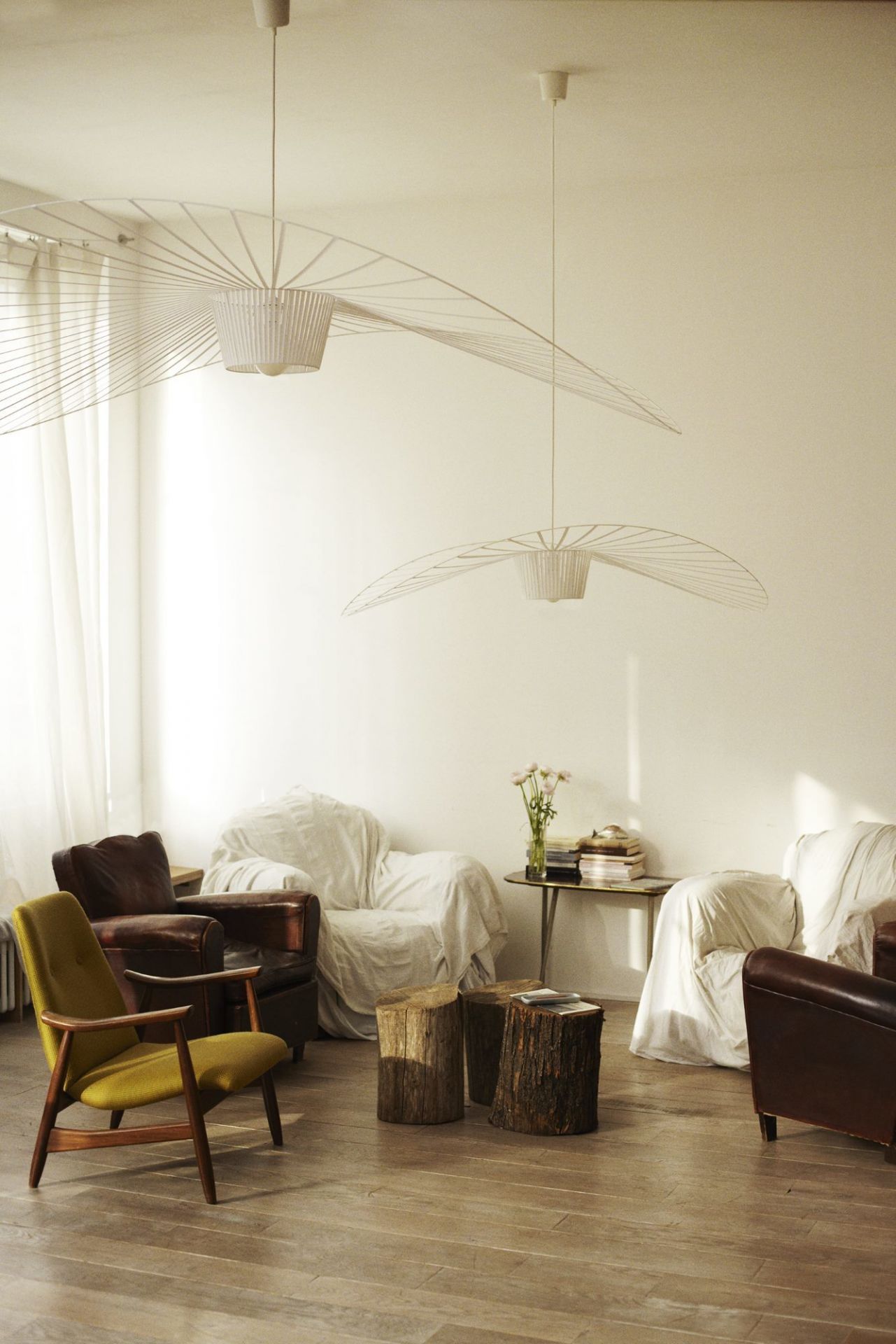Helle Wohnzimmer-Szene mit zwei großen, weißen Vertigo Pendelleuchten von Petite Friture als stilvolle Beleuchtung.