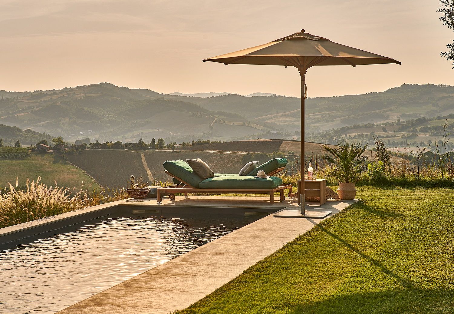 Weishäupl Teakschirm neben Pool und Liege mit Blick auf toskanische Landschaft, ideal für entspannte Sommertage.
