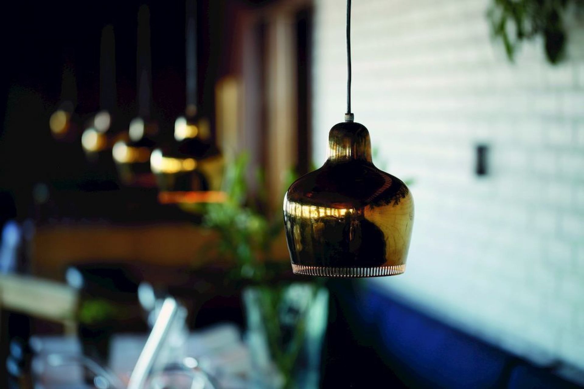 A330S Golden Bell Pendelleuchte von Artek, goldene Hängelampe im Interieur mit weiteren Lampen im Hintergrund.