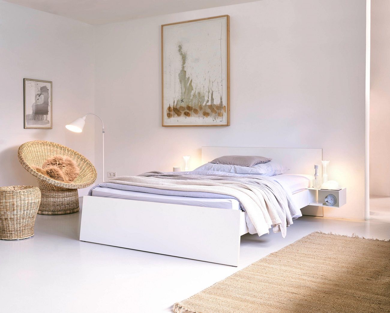 Weißes Bett mit Nachttisch zum Einhängen von Richard Lampert, minimalistisches Schlafzimmer Design mit Teppich und Korbsessel.