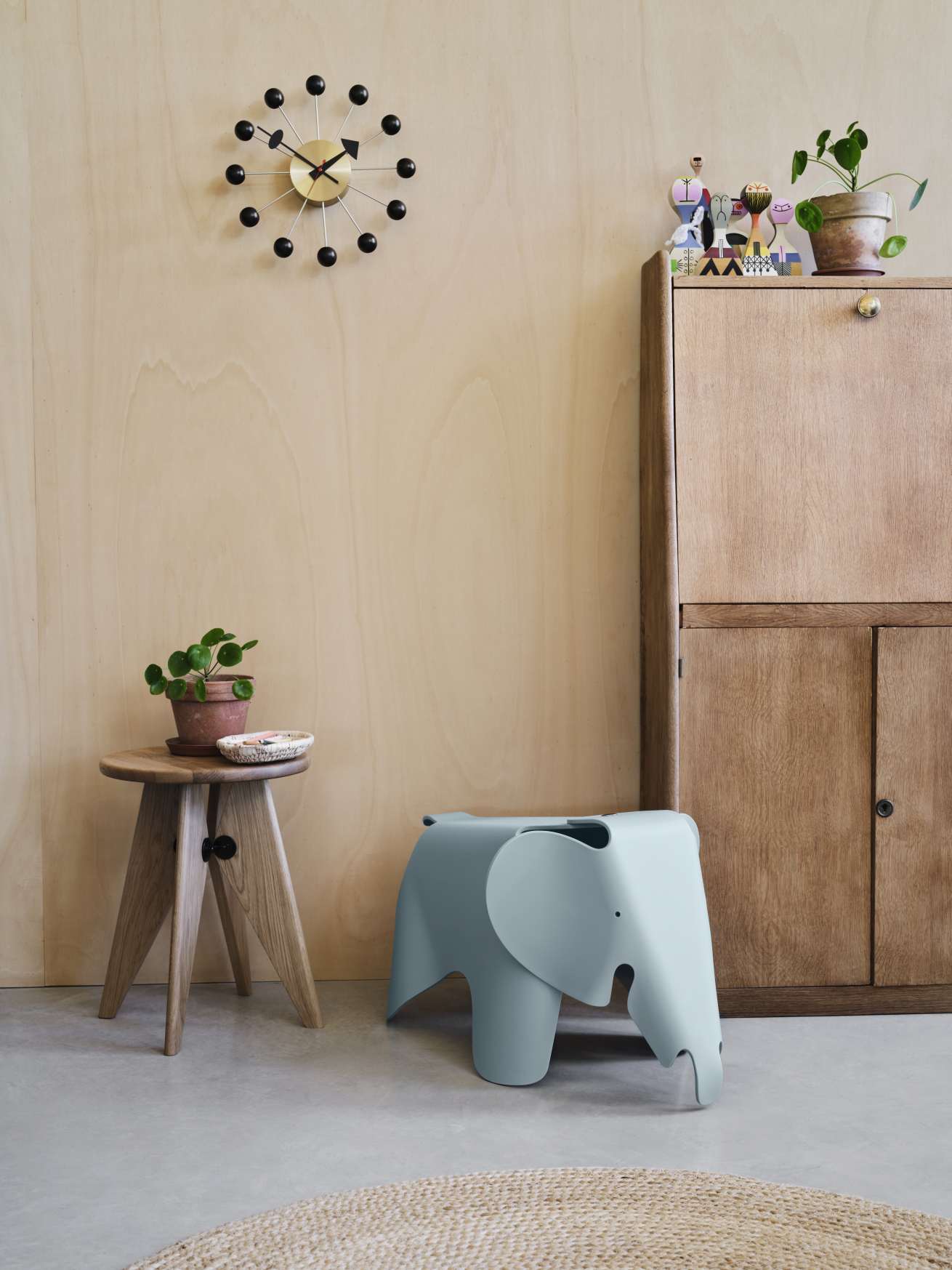 Blauer Vitra Eames Elefant Kinderhocker aus Kunststoff neben Holzhocker und Vintage-Schrank im Interieur.