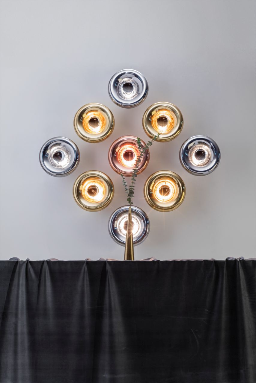 Mehrere Tom Dixon Void Surface LED-Wandleuchten in Gold, Silber und Kupfer an einer Wand.