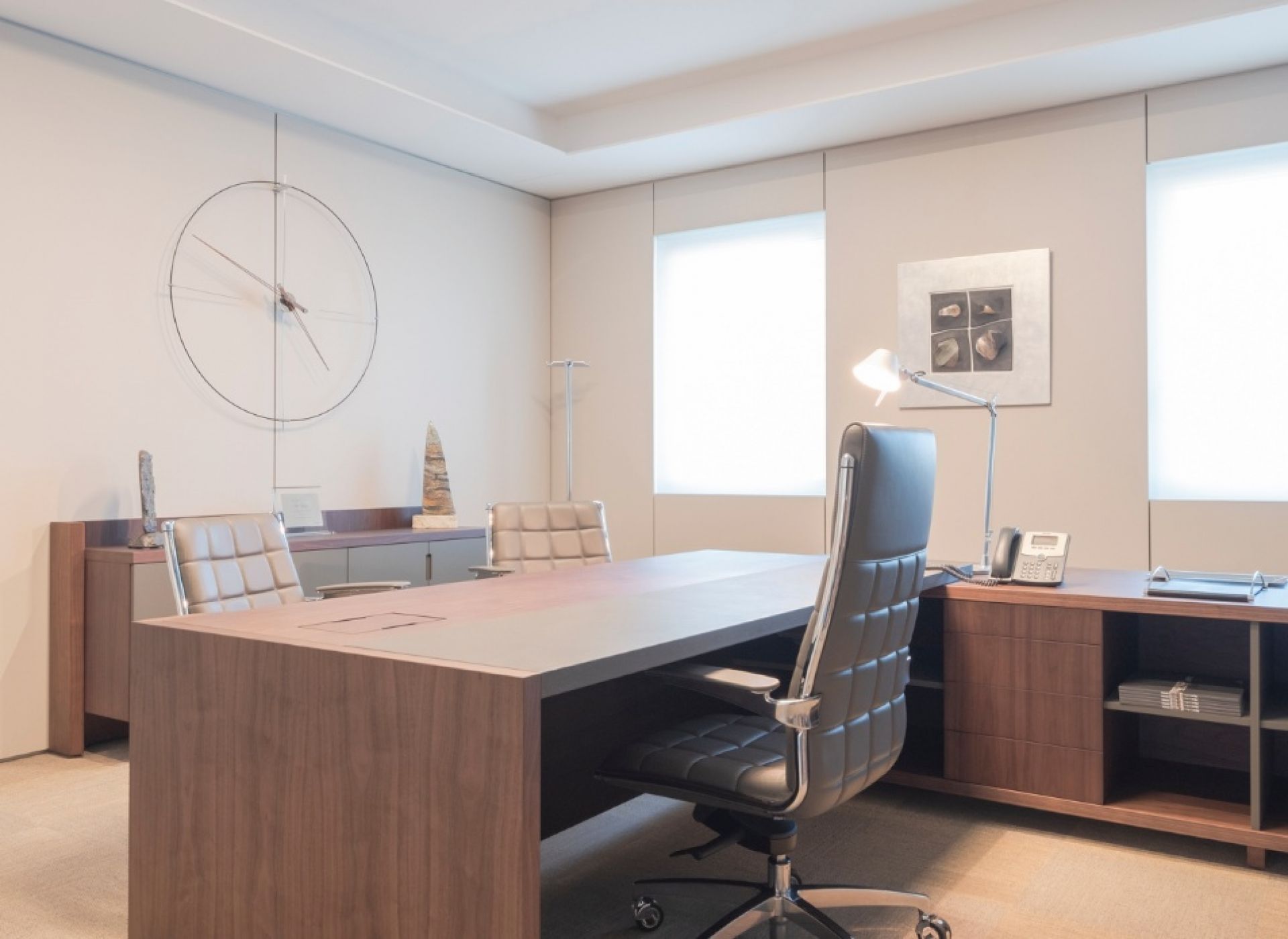 Büro mit Bilbao Wanduhr von Nomon, minimalistische Uhr in Schwarz-Weiß an der Wand.