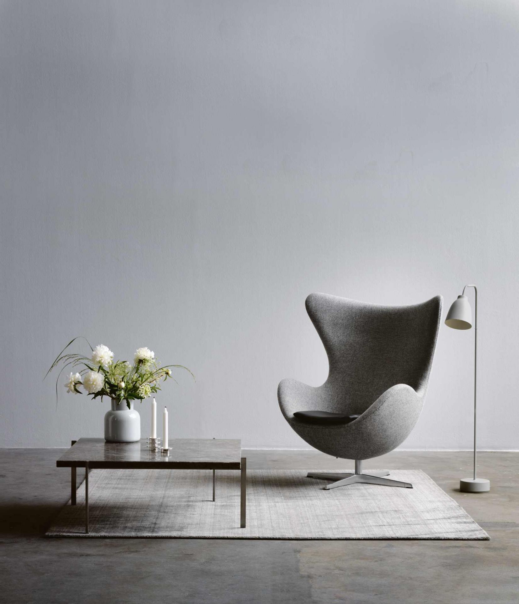 PK61 Couchtisch von Fritz Hansen mit Blumen und Kerzen im modernen Wohnzimmer.