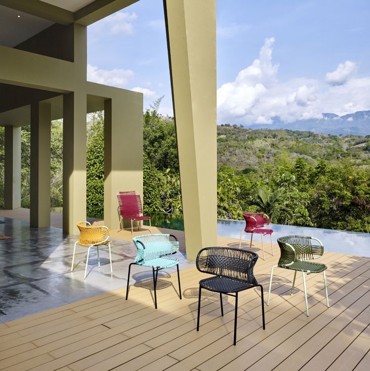 Mehrere Cielo Armlehnstühle in verschiedenen Farben auf einer Terrasse mit Pool und Landschaft. Outdoor Möbel.