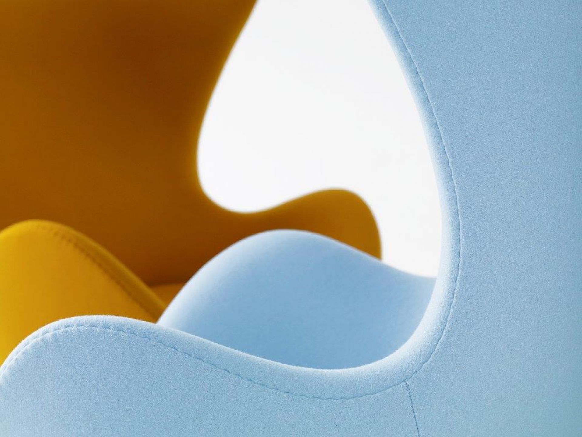 Detailaufnahme: Blauer und gelber "Das Ei" Sessel, Designklassiker von Fritz Hansen. Polstermöbel für Wohnzimmer.