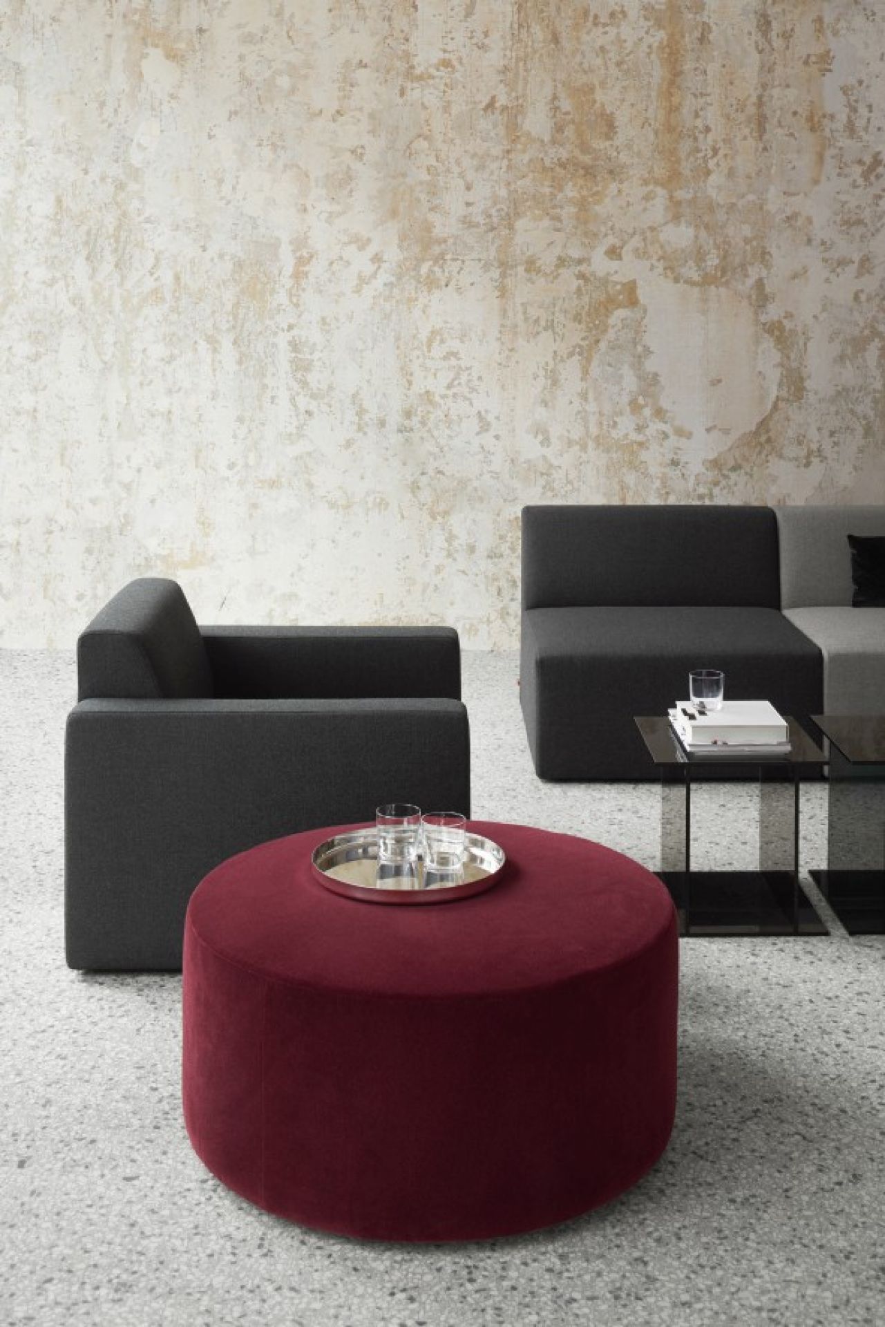 SF06 Kerman Modulsofa von e15 in Anthrazit und ein roter Hocker mit Tablett.