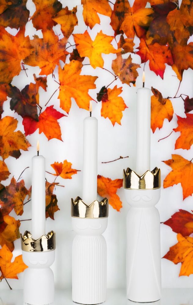 Räder Königslicht Kerzenständer 3er Set mit goldenen Kronen und brennenden Kerzen vor Herbstlaub.