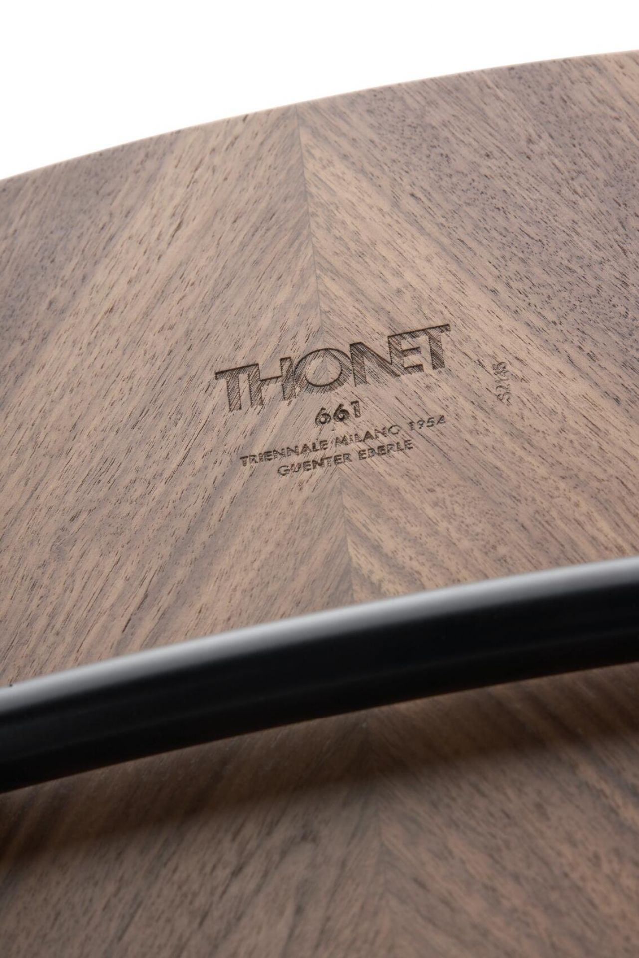 Detailaufnahme der Holzoberfläche des Thonet S 661 Stahlrohrstuhls mit eingraviertem Thonet-Logo und Stahlrohr-Element.