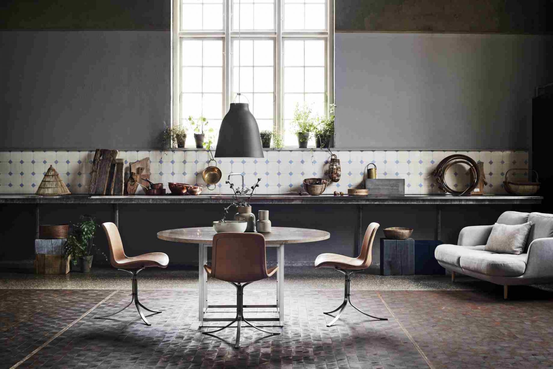 Helles Interieur mit Fritz Hansen Lune Sofa, grauem 2-Sitzer und Esstisch mit Stühlen.