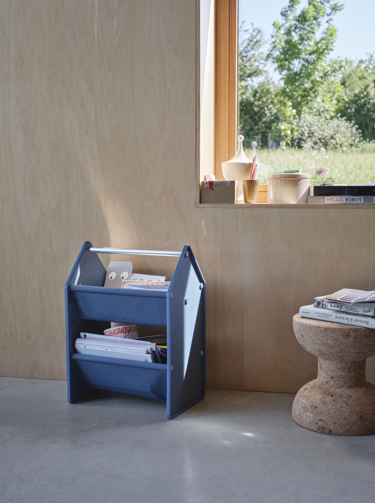 Blaue Vitra Drop Box Aufbewahrungsbox mit zwei Fächern, gefüllt mit Zeitschriften und Papier.