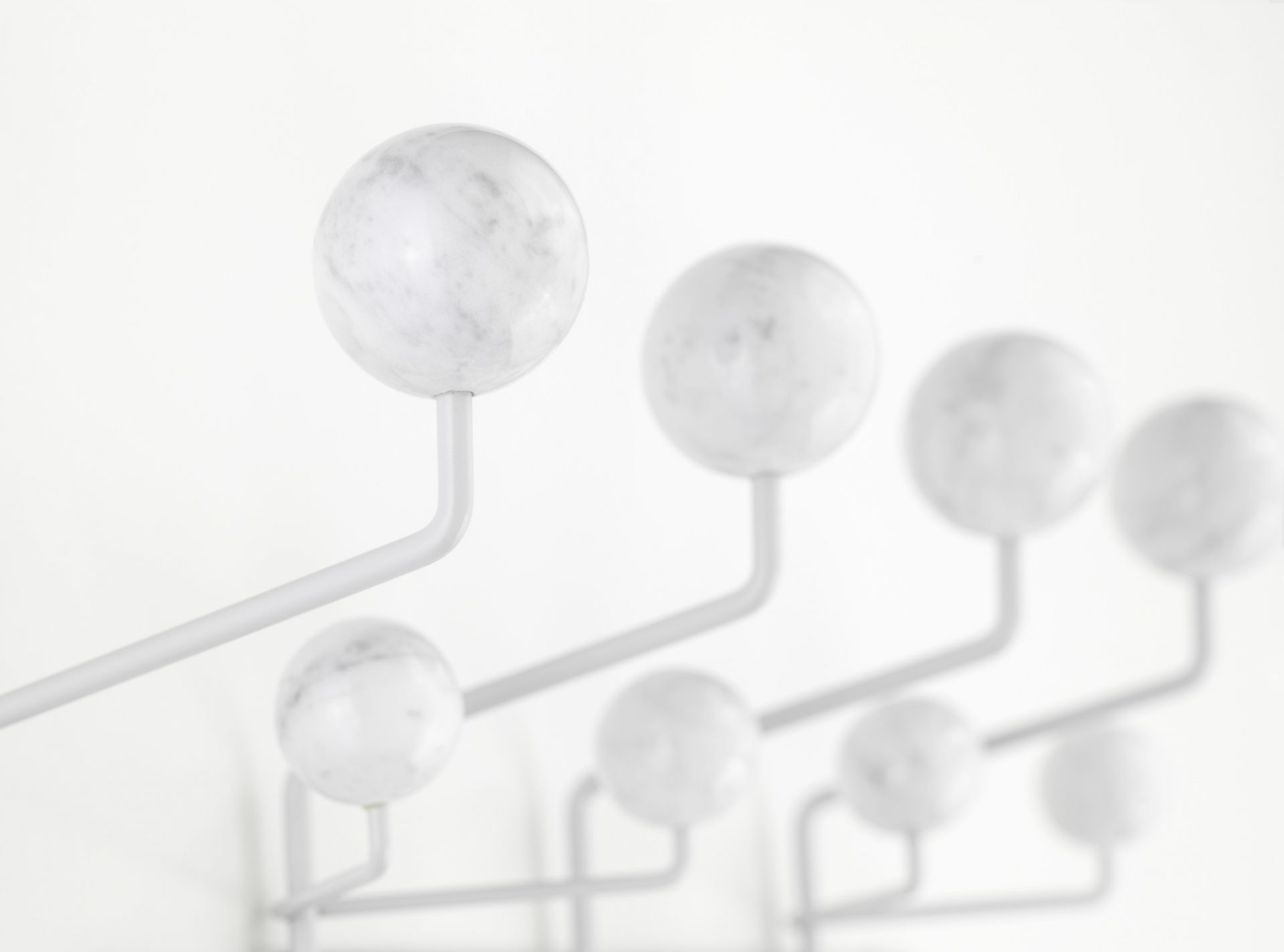 Detailaufnahme der Eames Hang it all Garderobe in Marmor Optik, ein Designklassiker für stilvolle Flure.