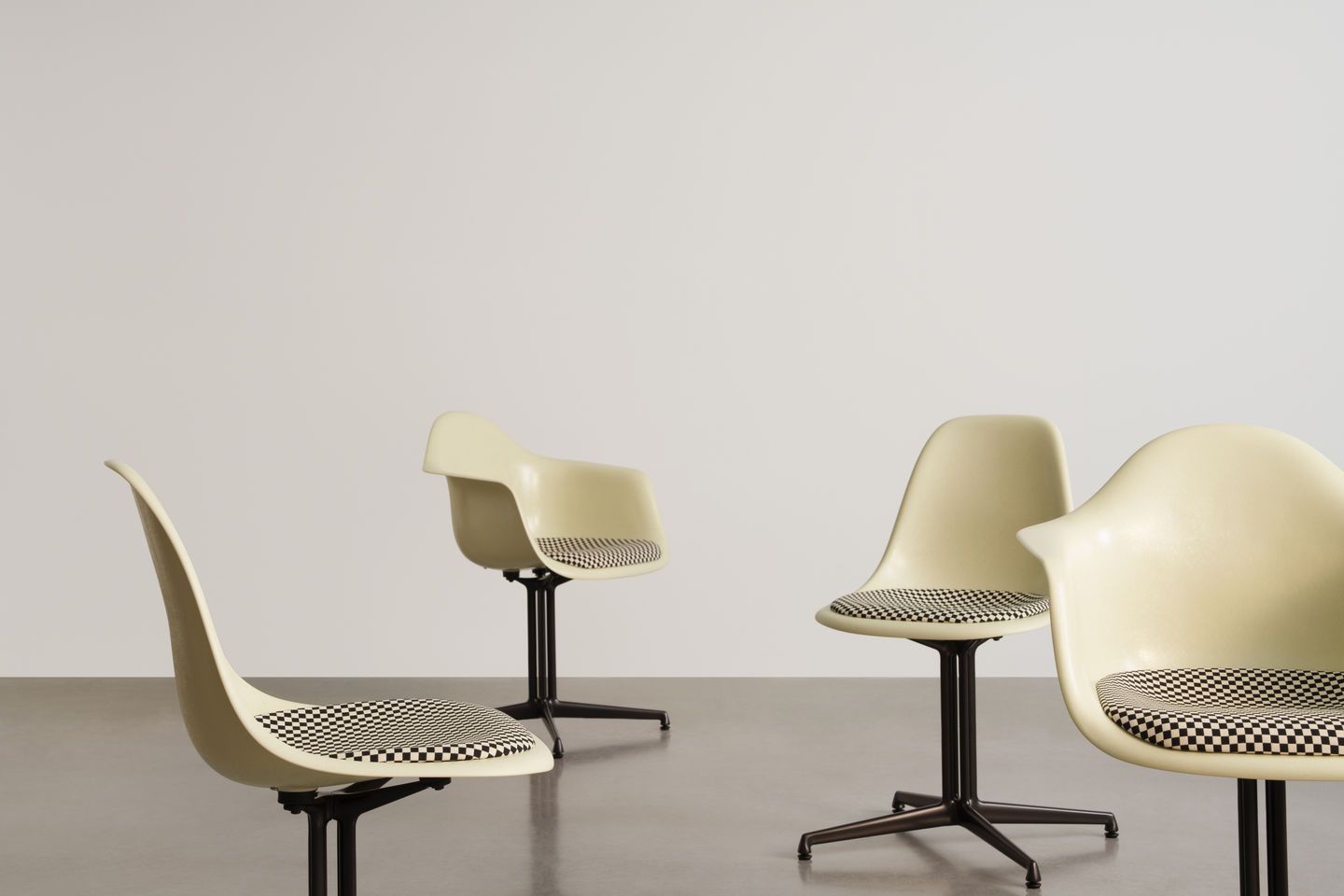 Vitra Eames Plastic Chair DAL mit Sitzpolster, hellgelbe Schale, schwarzes Untergestell, Schachbrettmuster auf Sitzfläche.
