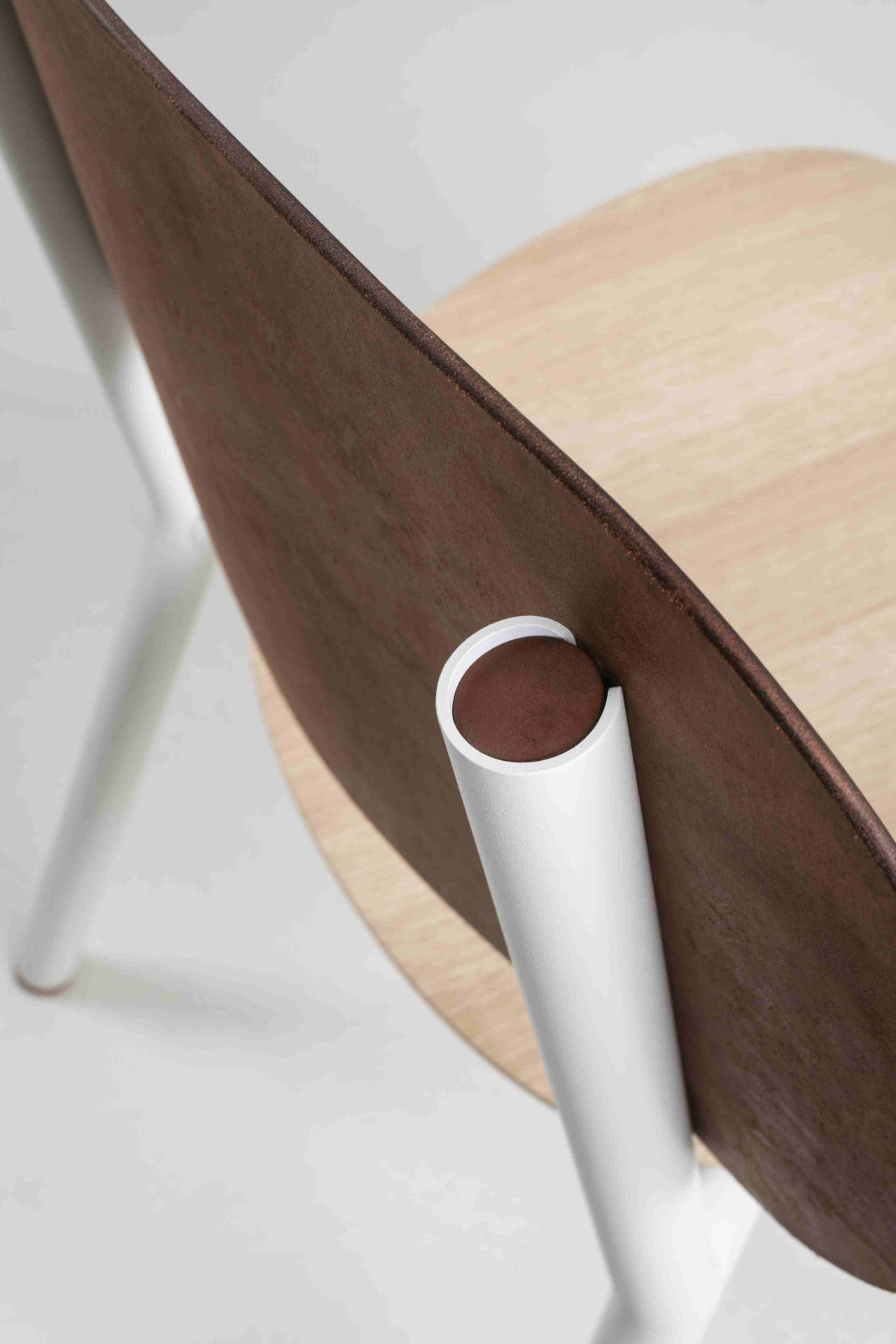 Detailaufnahme des Emil Stuhls: Holzlehne, helle Sitzfläche und weiße Beine. Designstuhl für Esszimmer.