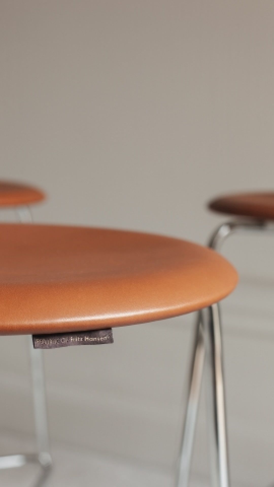 Detailaufnahme: Fritz Hansen Dot Hocker mit Walnuss-Sitzfläche und Chromgestell, modernes Möbeldesign.