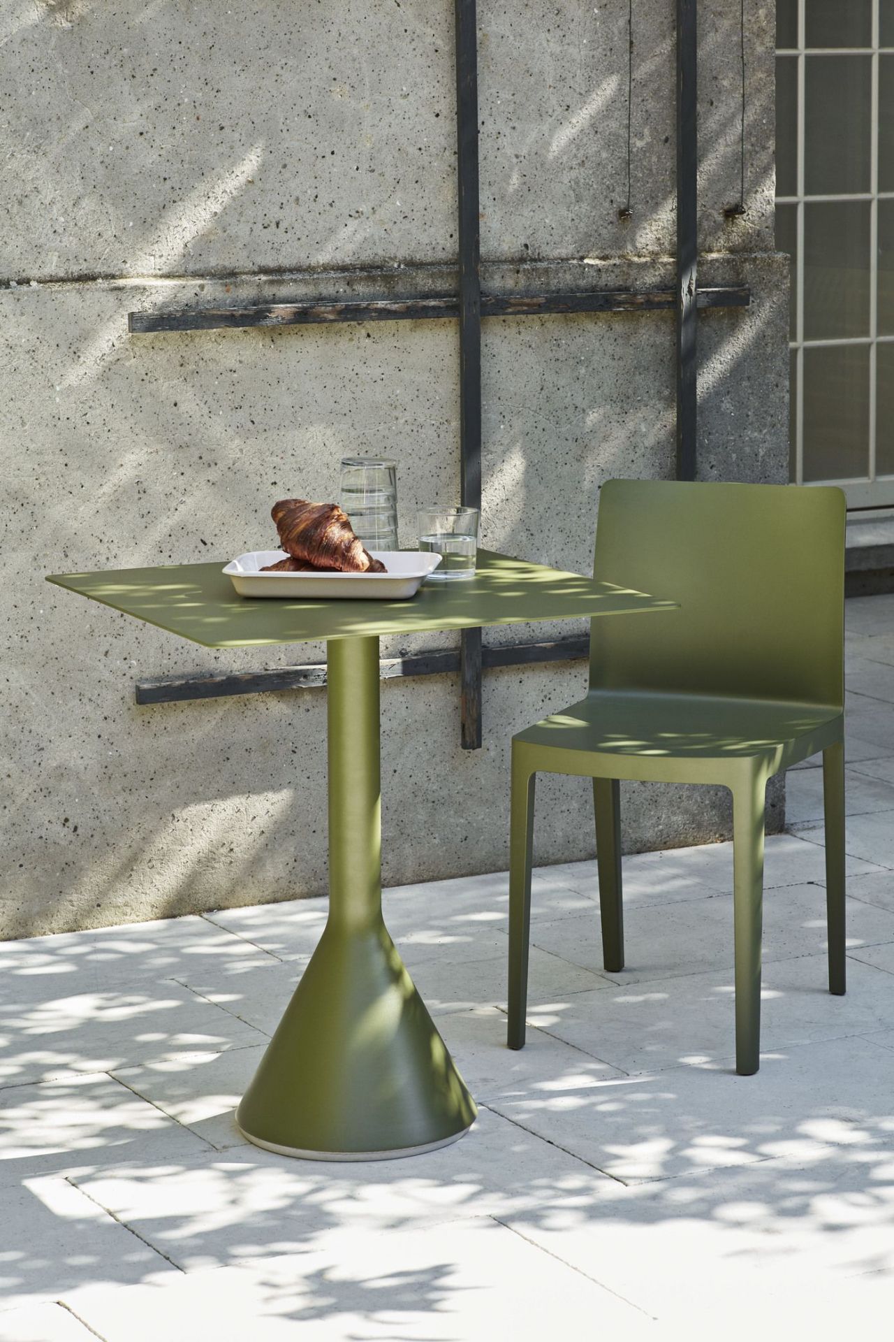 Olivefarbener Élémentaire Stuhl und Tisch im Freien mit Croissant und Getränken für eine entspannte Atmosphäre.