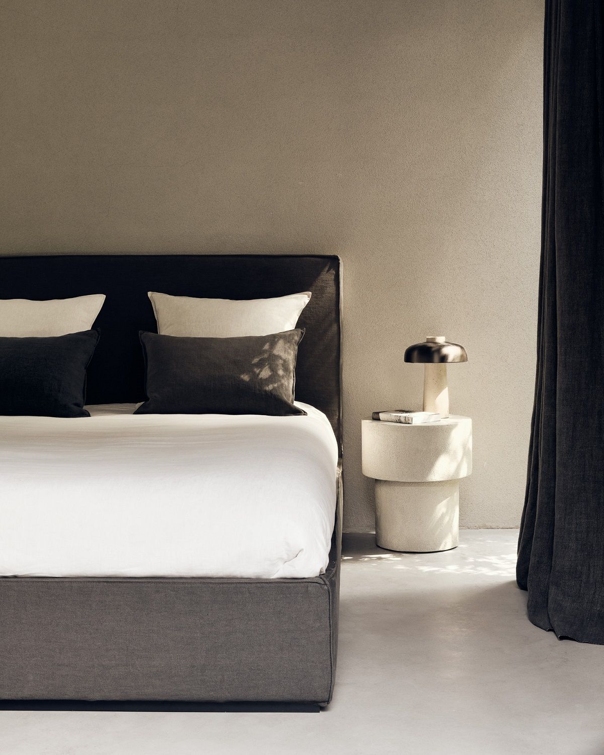Nahaufnahme eines Bettes mit Nachttisch, der Ethnicraft Elements Couchtisch in Off White zeigt.