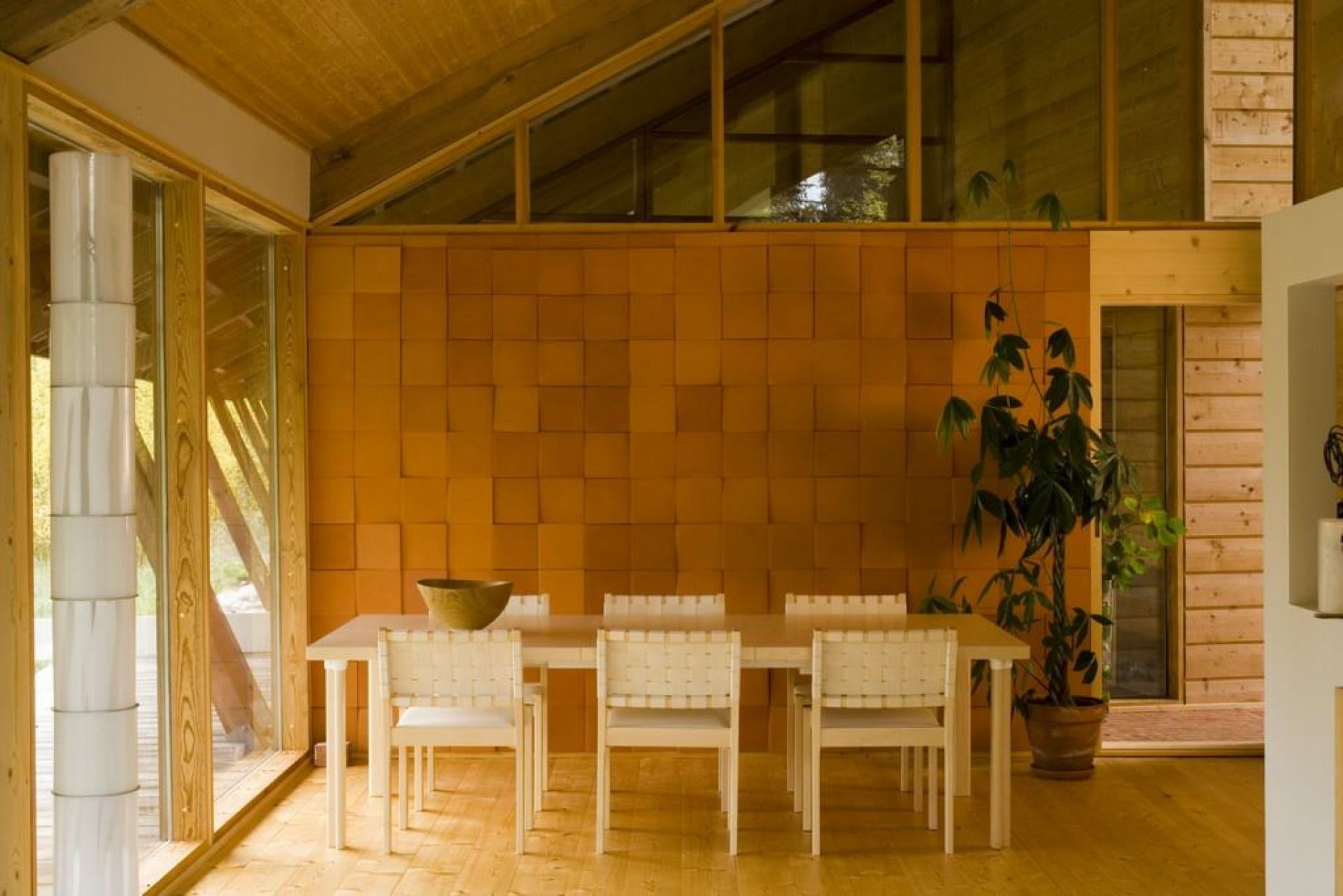 Esszimmer mit Holztisch und sechs weißen Artek 611 Stühlen mit Stoffbespannung vor einer Terrakotta-Wand.
