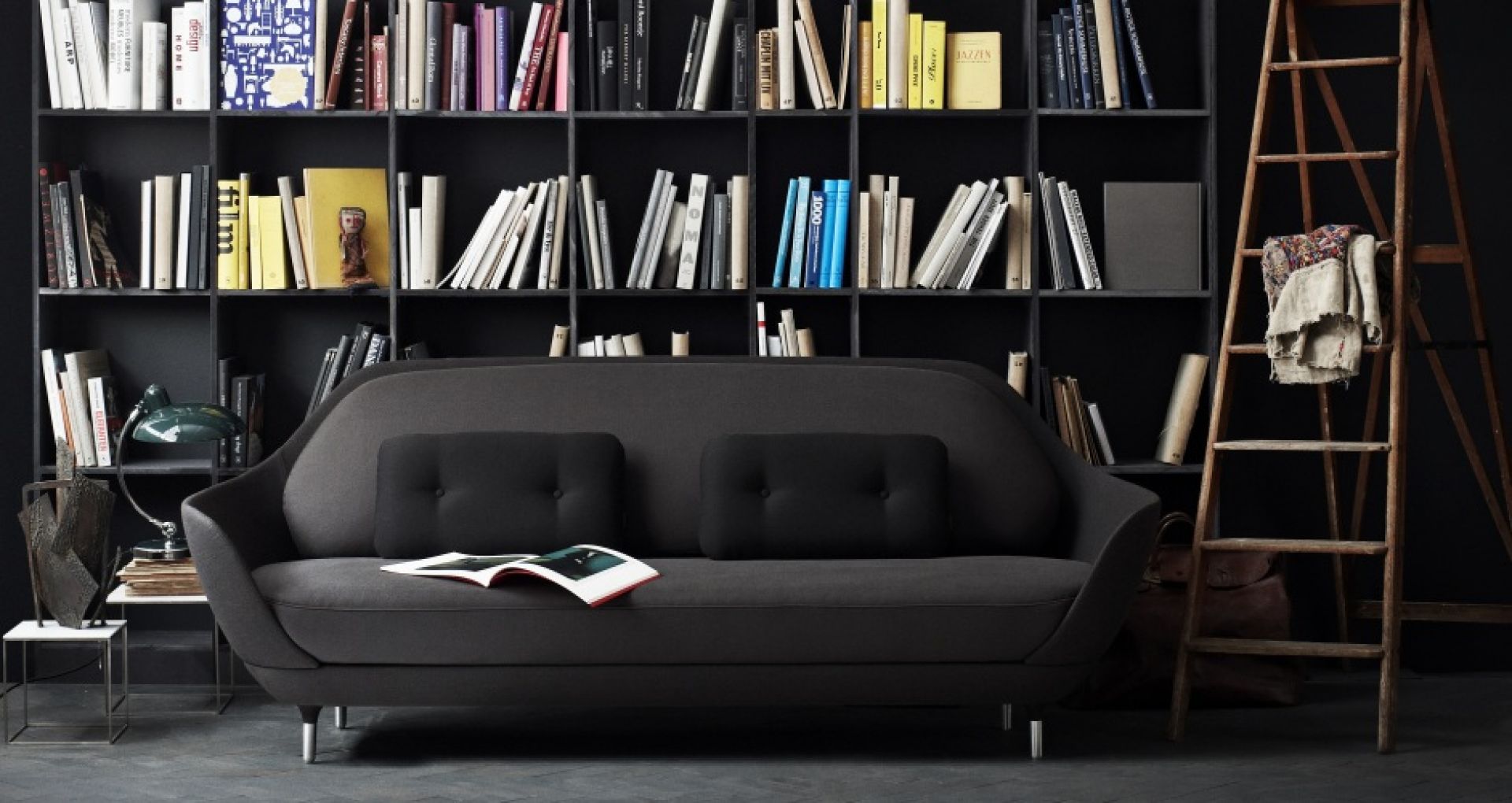 Graues Favn Sofa von Fritz Hansen mit schwarzen Kissen vor einem Bücherregal und einer Leiter.