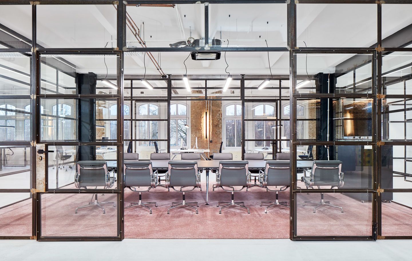 Konferenzraum mit Soft Pad Chair EA205 von Vitra, graue Ledersessel an langem Tisch auf rosa Teppich.
