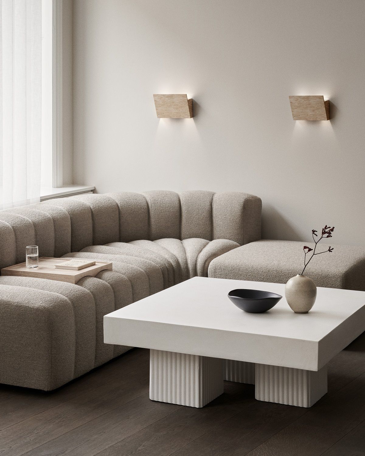 Heller Wohnraum mit Gear Square Couchtisch von Norr11, stilvollem Sofa und Wandleuchten.