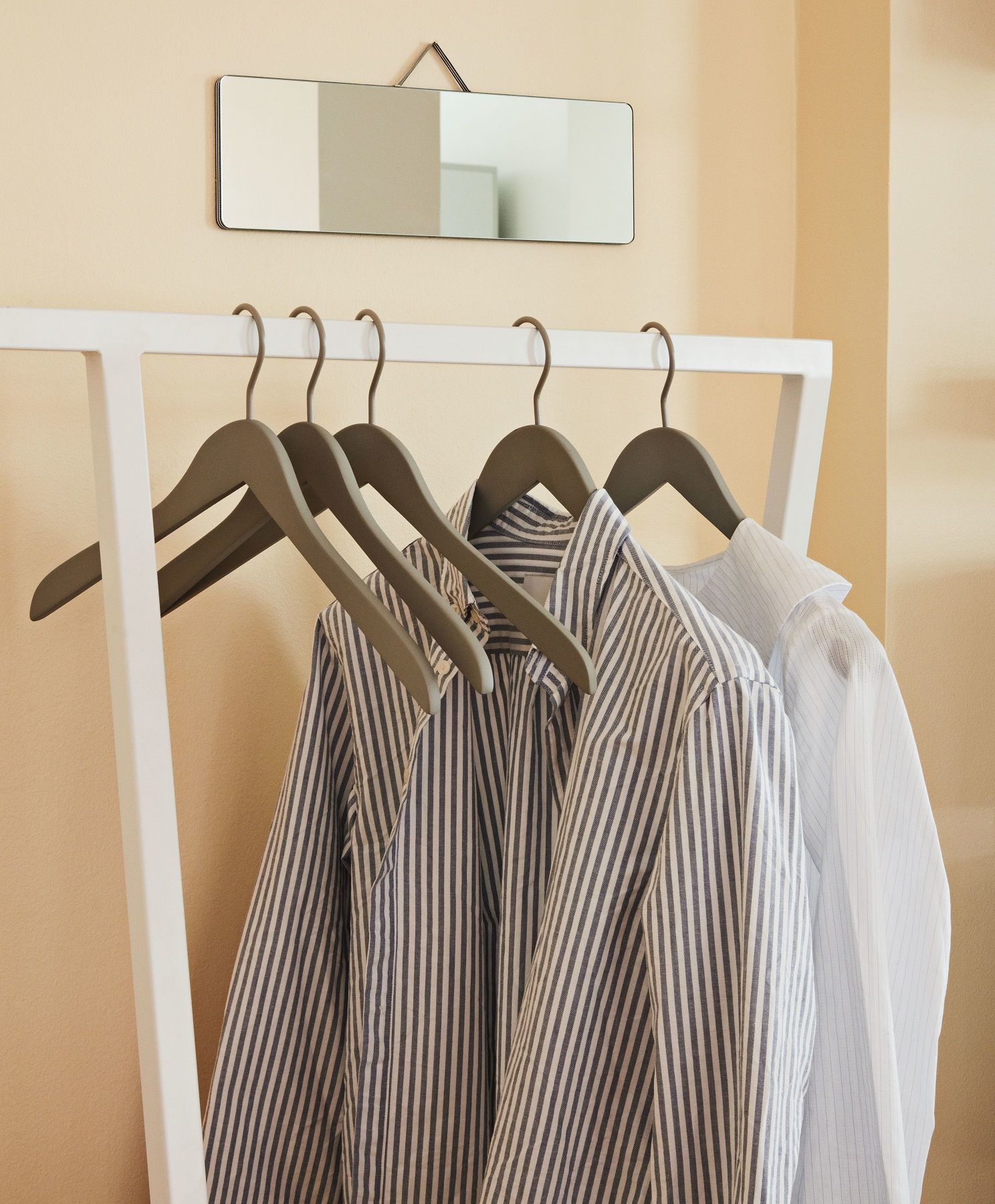 Weiße Loop Stand Garderobe von Hay mit Hemden und Spiegel an der Wand.