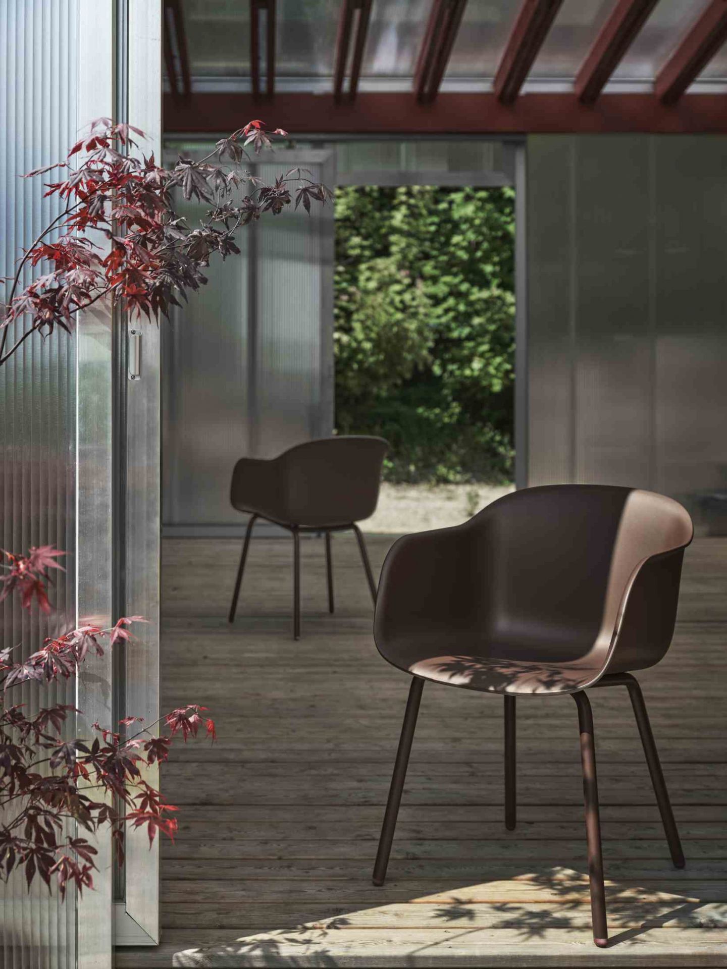 Brauner Fiber Armlehnstuhl von Muuto für den Außenbereich auf einer Holzterrasse. Design Gartenmöbel.