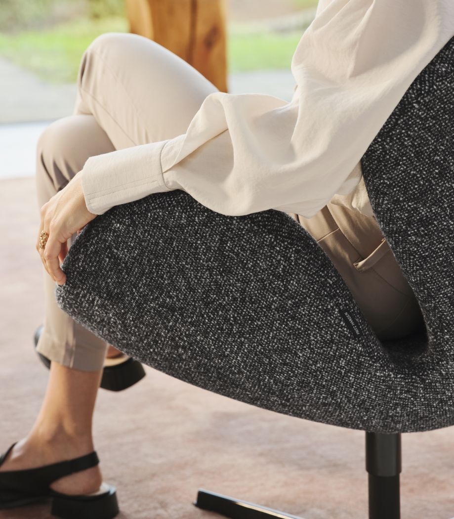 Frau sitzt im grauen Swan Sessel von Fritz Hansen, ein Designklassiker.