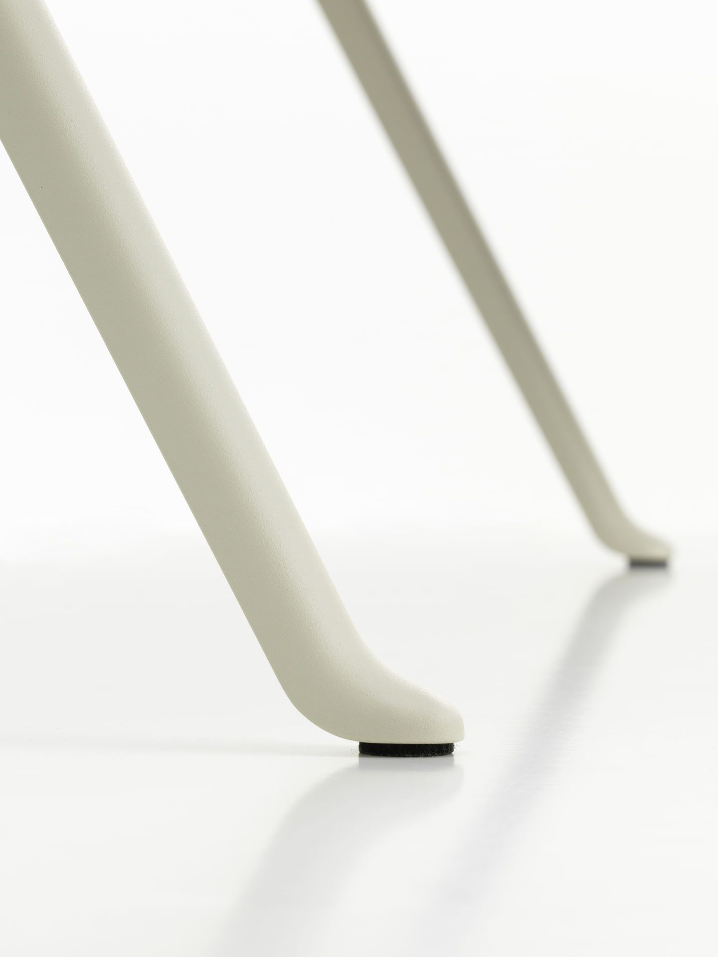 Detailaufnahme der hellgrauen Beine des Vitra Courier Schreibtischs mit schwarzen Filzgleitern auf einem weißen Hintergrund.