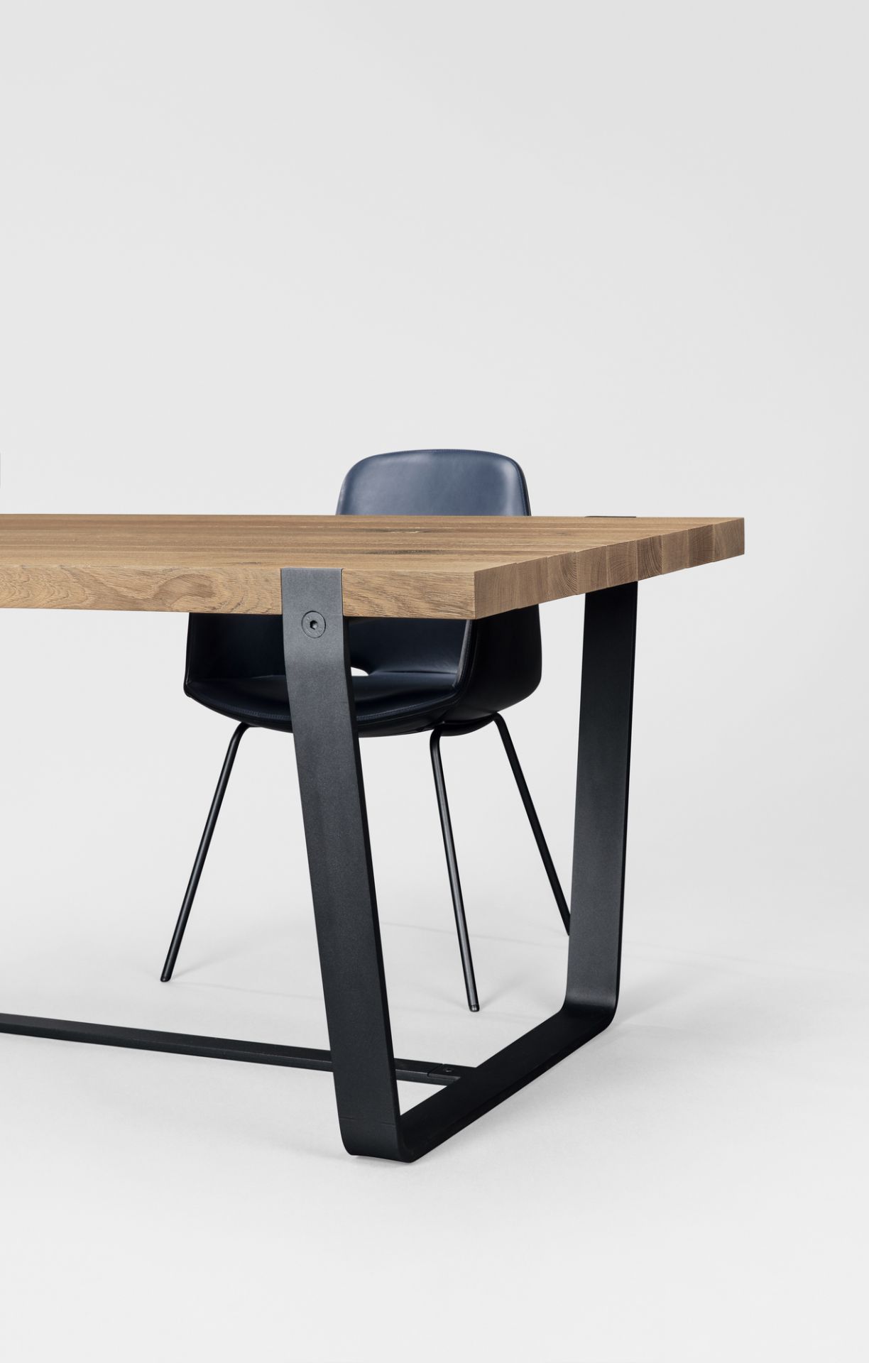 Detailansicht des Janua BB 11 Clamp Tisch Eiche mit schwarzem Stahlgestell und Stuhl.