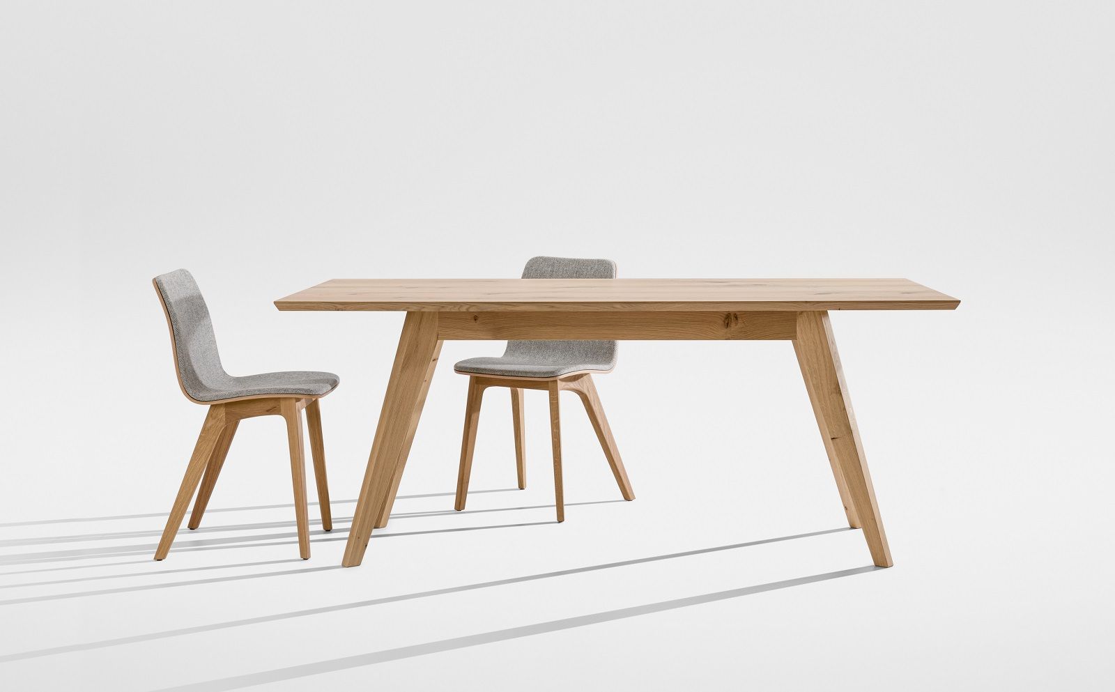 CENA Tisch, rechteckiger Esstisch aus hellem Holz mit zwei grauen Stühlen auf weißem Hintergrund.
