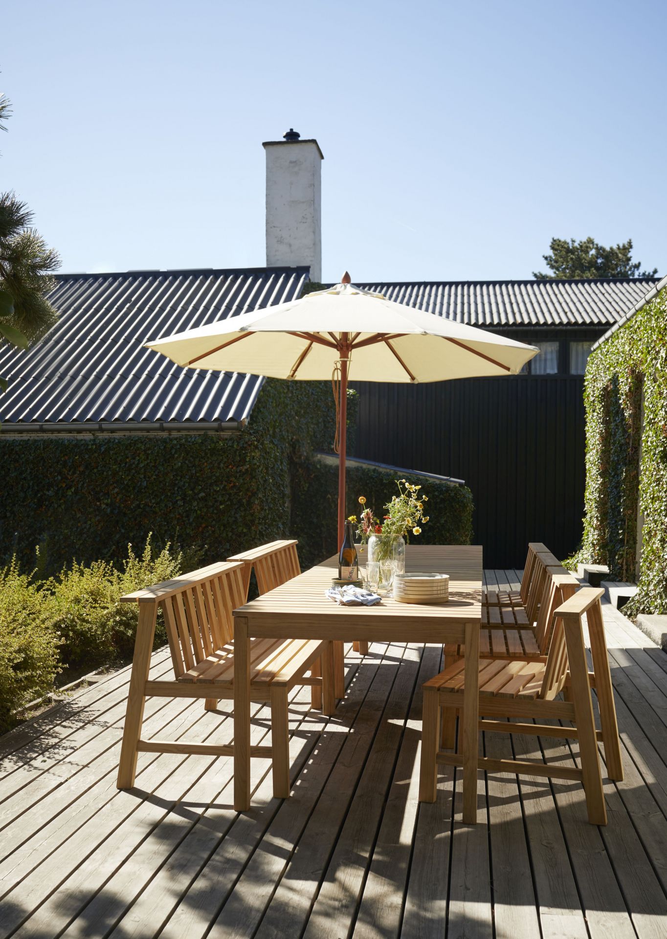 Cadence Bank Teak Gartengarnitur von Skagerak by Fritz Hansen mit Sonnenschirm auf Holzterrasse.