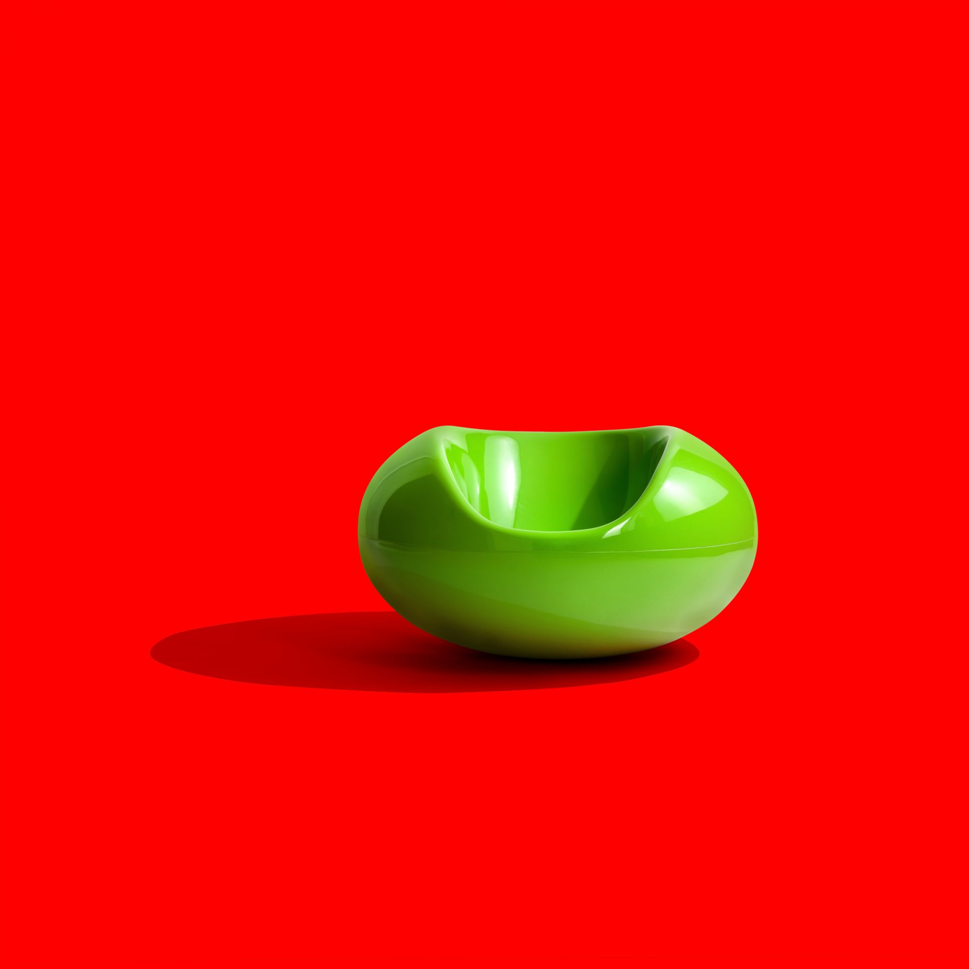 Grüner Pastil Stuhl von Eero Aarnio, ein moderner Designklassiker auf rotem Hintergrund.
