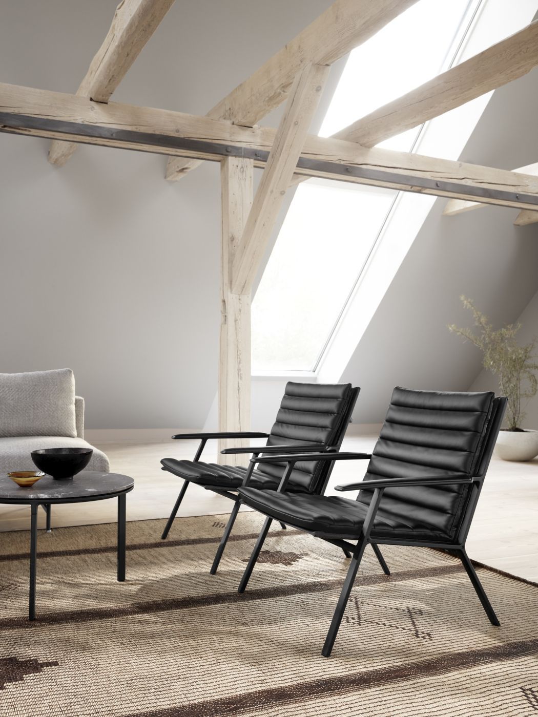 Zwei schwarze Vipp Lounge Stühle aus Leder im modern eingerichteten Dachgeschoss mit Teppich.