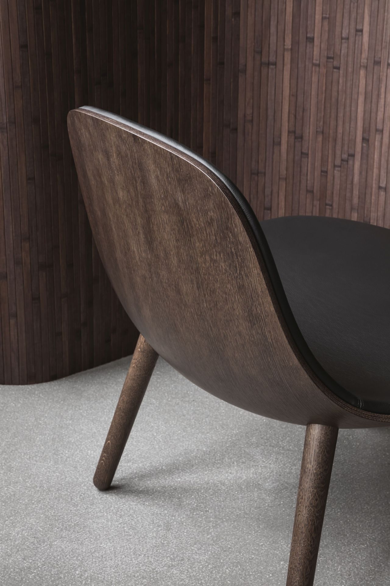 EVA SOLO Abalone Lounge Stuhl aus geräucherter Eiche, Detailansicht von hinten mit schwarzer Sitzfläche.