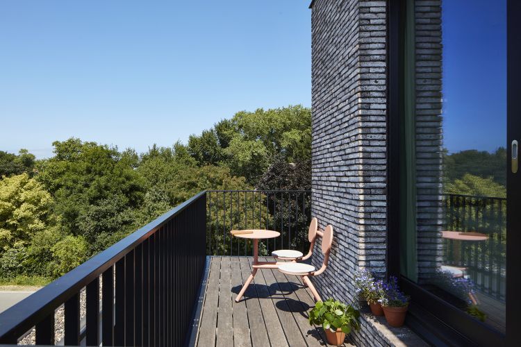 Extremis Bistroo Outdoor-Möbel: Stuhl-Tisch-Kombination aus rosafarbenem Metall auf einem Balkon mit Holzboden.
