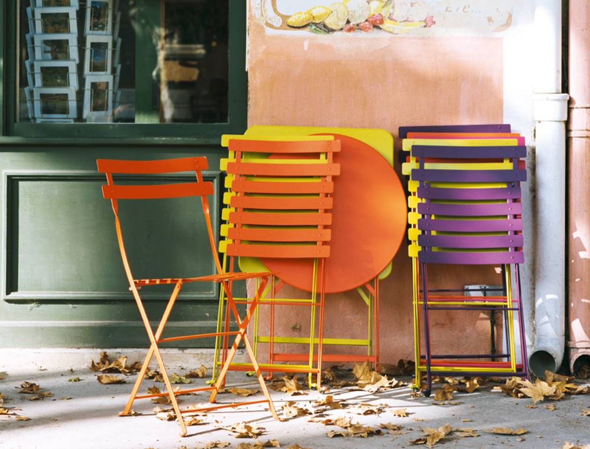 Fermob Bistro Klapptisch und Stühle für den Außenbereich in Orange, Gelb und Lila.