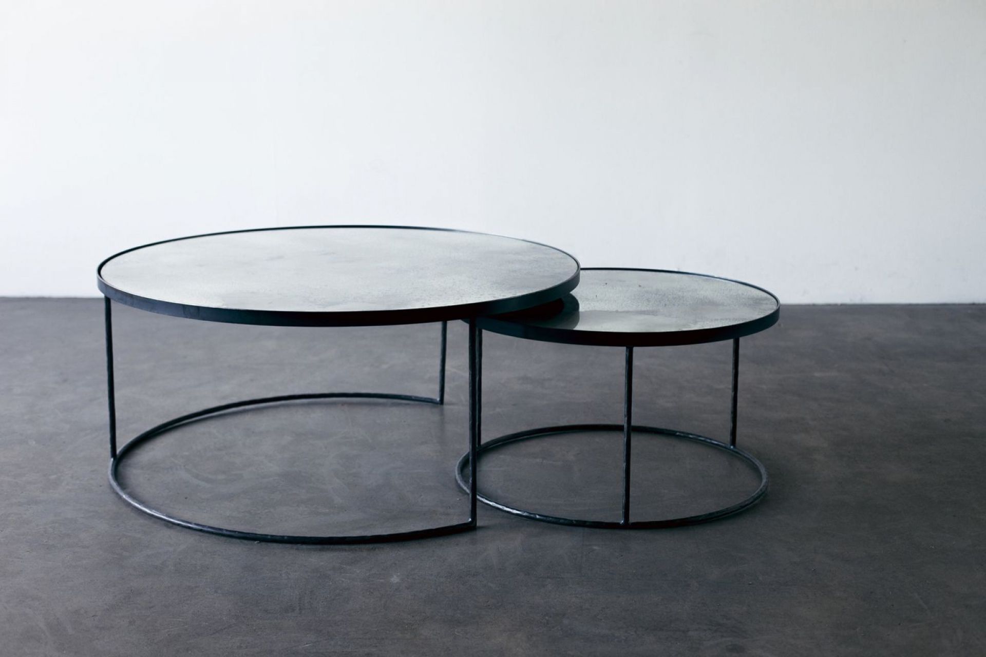 Ethnicraft Couchtisch Set: Zwei runde Beistelltische mit schwarzem Metallgestell und grauer Tischplatte.