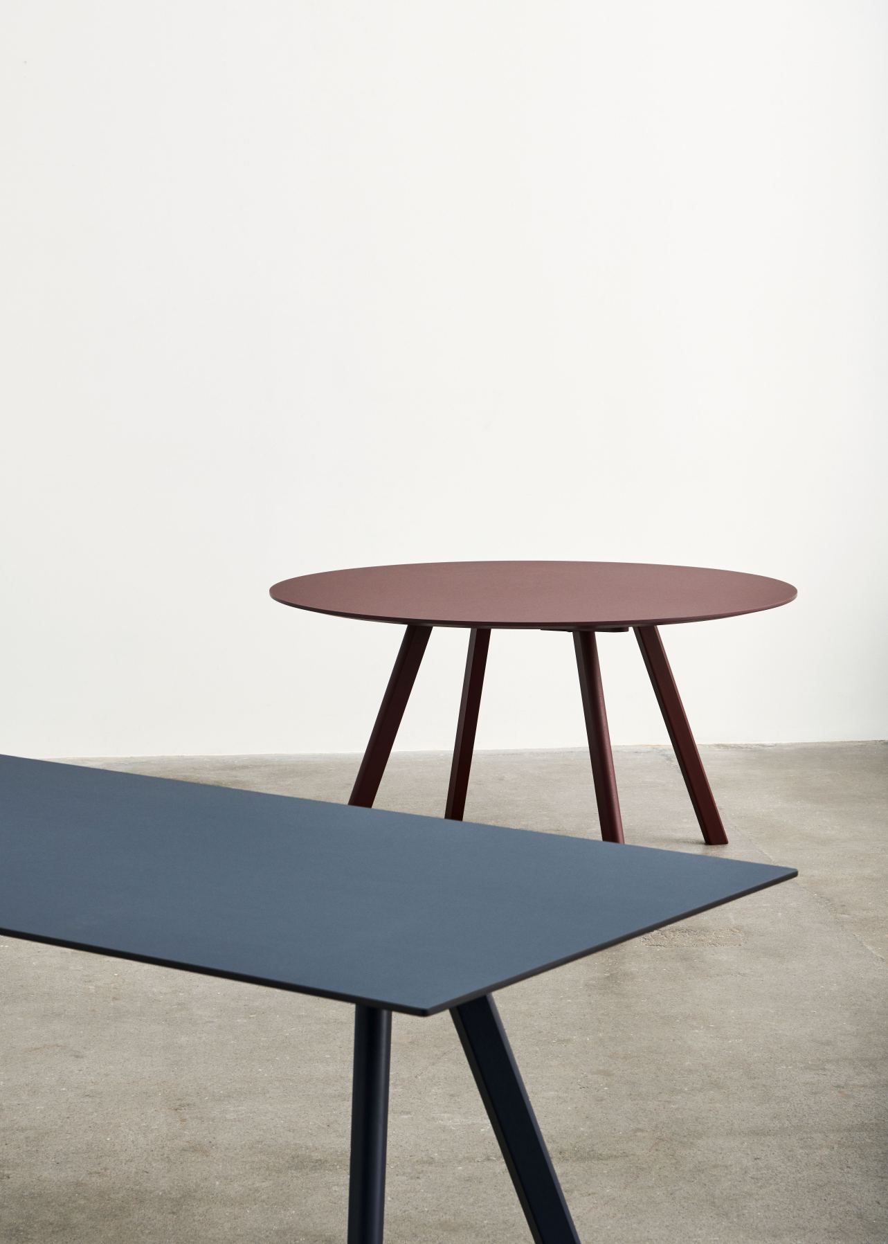 Nahaufnahme von zwei Tischen, darunter ein runder Copenhague Table CPH 25 Tisch von Hay.