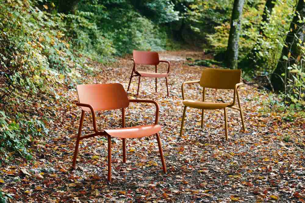Drei farbige Fermob Sessel der Studie Lounge Outdoor Kollektion stehen im herbstlichen Wald.