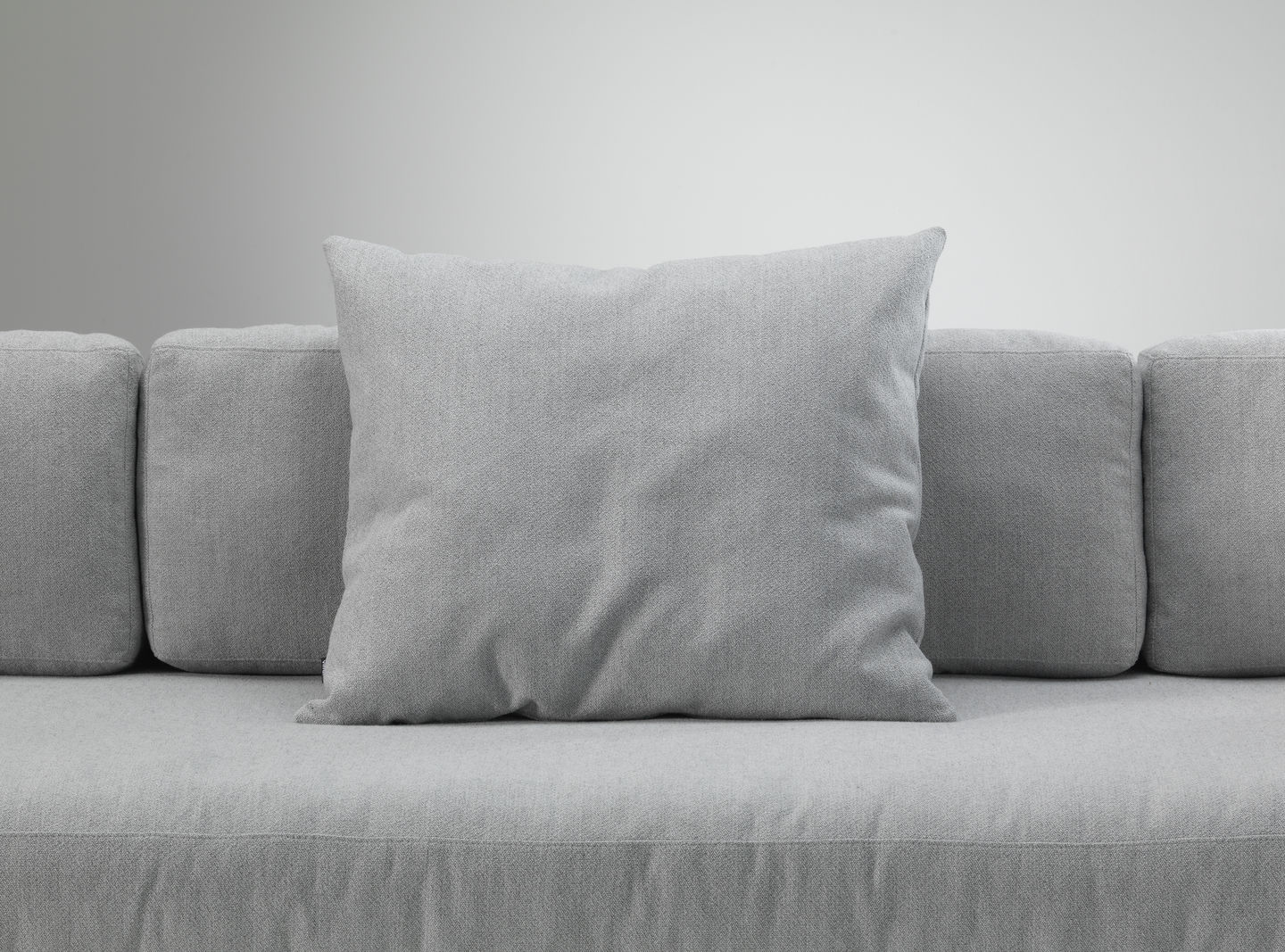 Graues Vitra Kissen / Sofakissen aus Stoff auf einem grauen Sofa, Nahaufnahme.