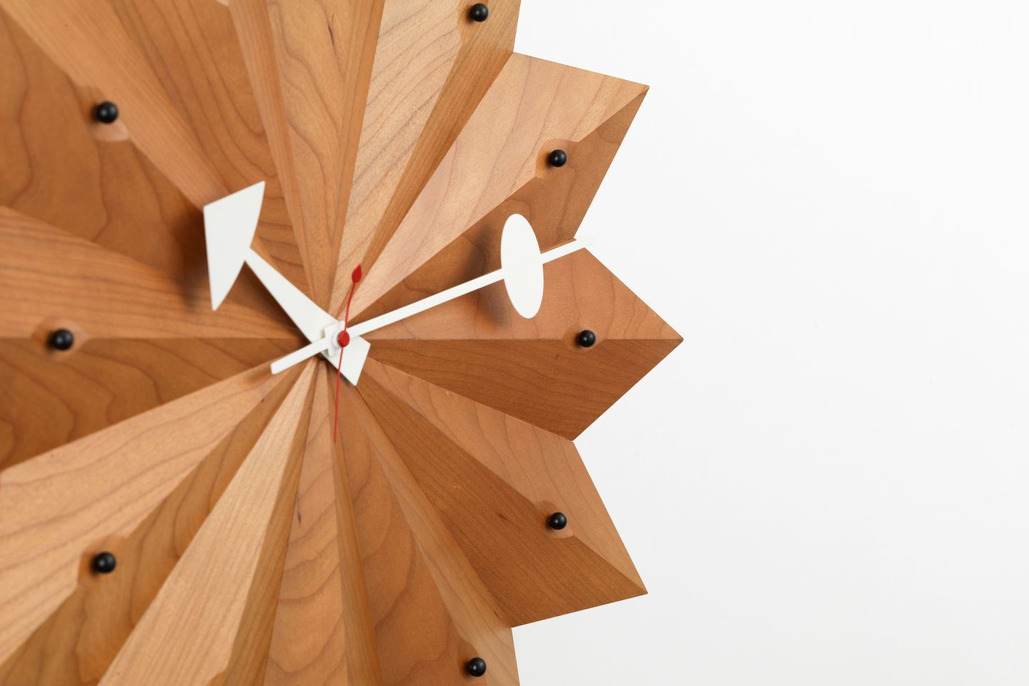 Detailaufnahme der Vitra Fan Clock Wanduhr aus Kirschbaumholz mit weißen Zeigern.