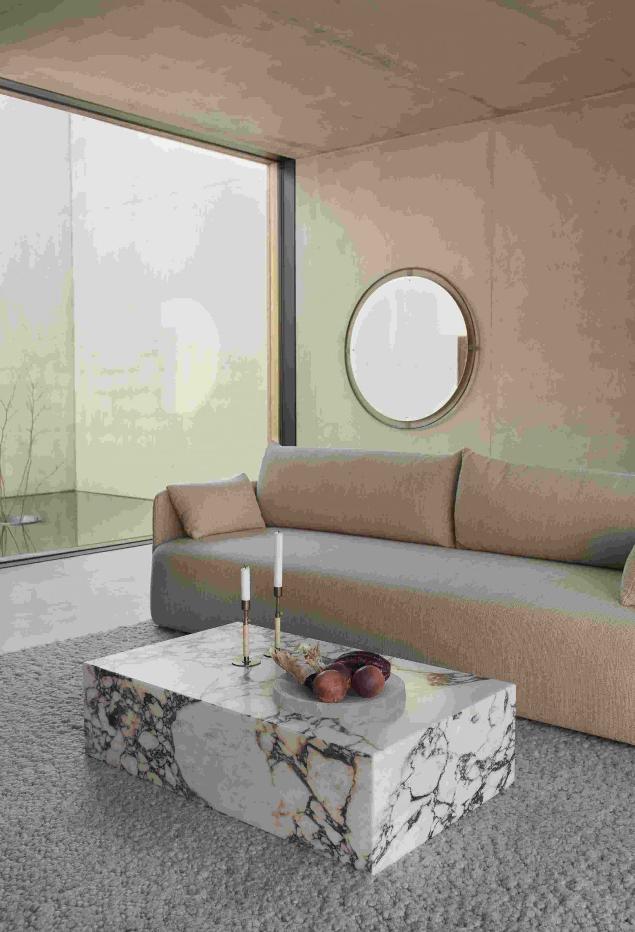Audo Copenhagen Plinth Tisch aus Marmor im Wohnzimmer mit Sofa und Dekoration.