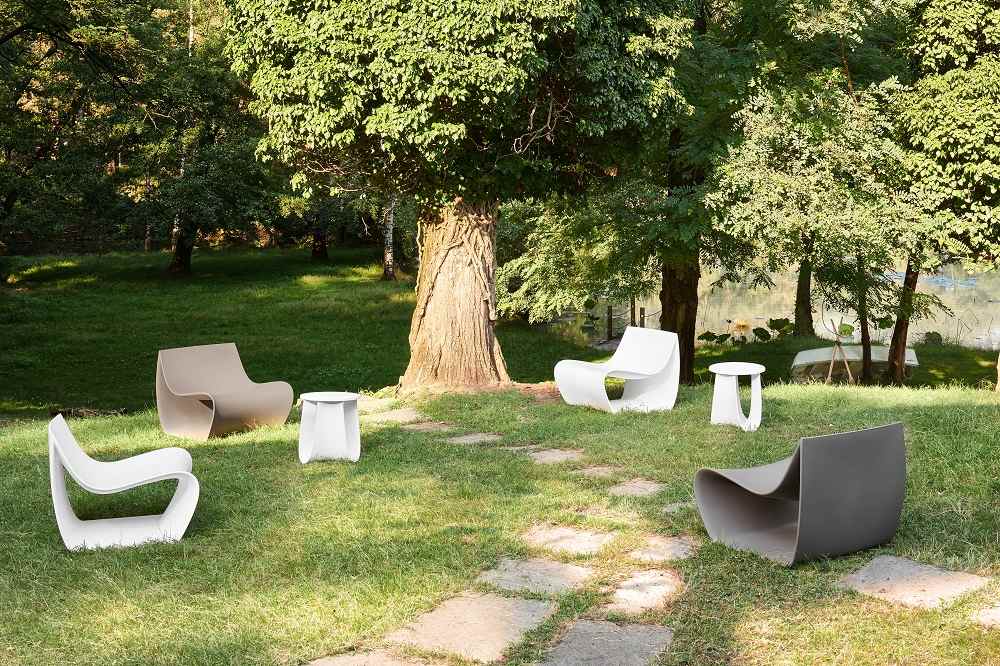 Mehrere MDF Italia SIGN MATT Sessel für den Innen- und Außenbereich in einem Garten mit Bäumen.